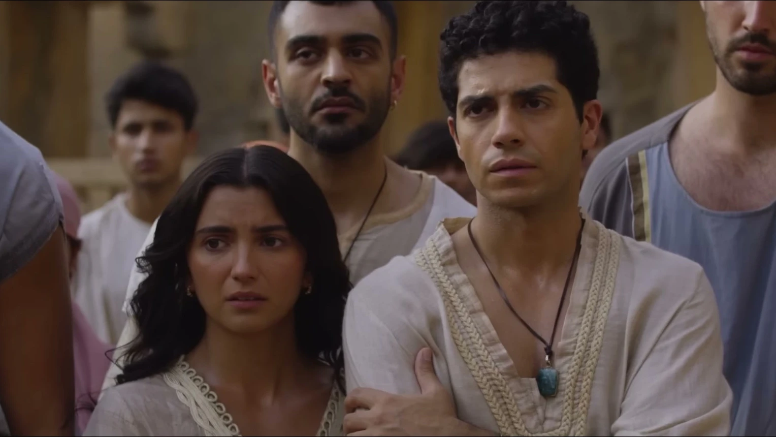 Mena Massoud as Daniel stands with Susanna and other young exiles in Babylon.