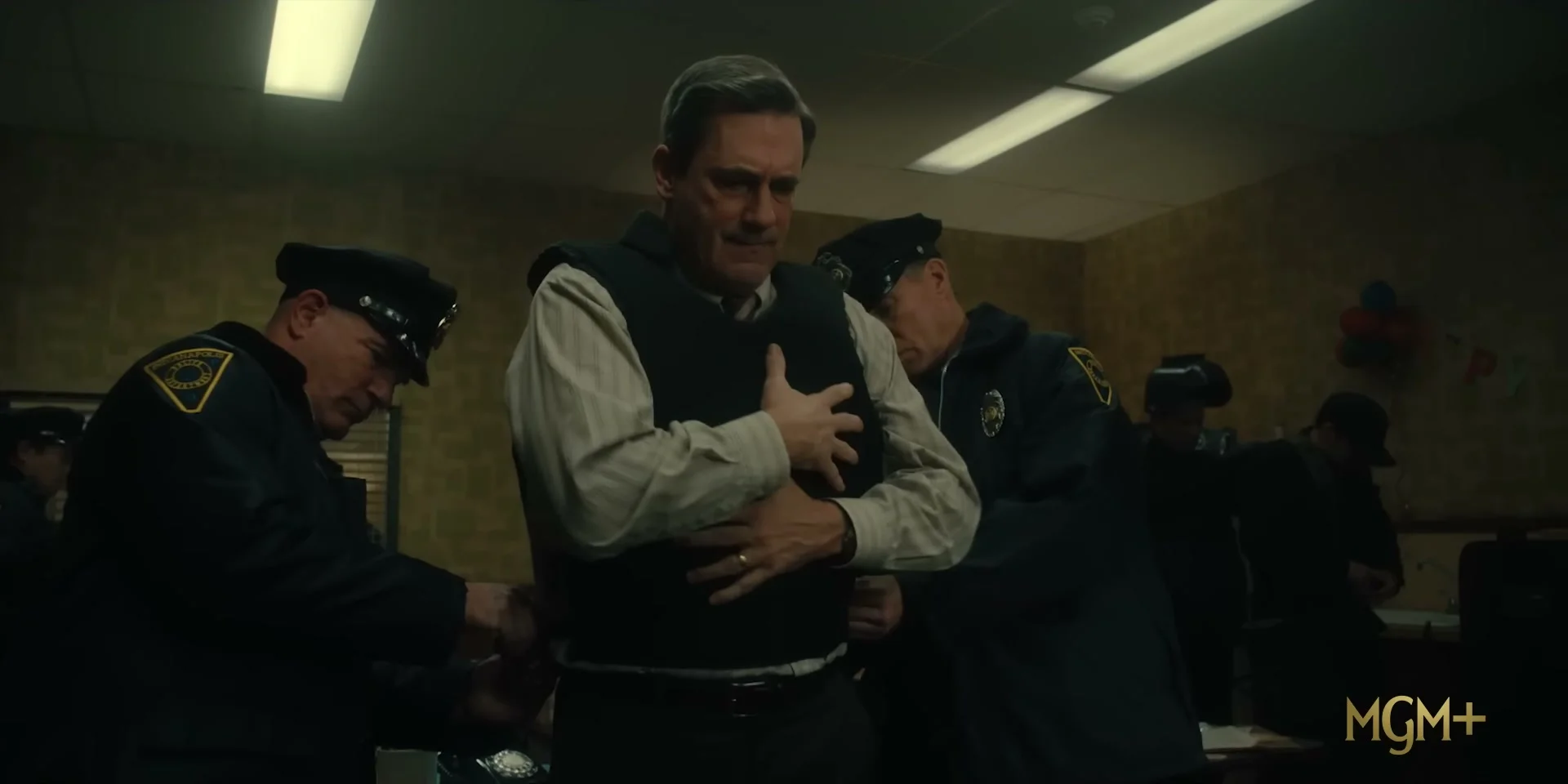Police officers secure Fred Heckman after a tense moment in American Hostage.