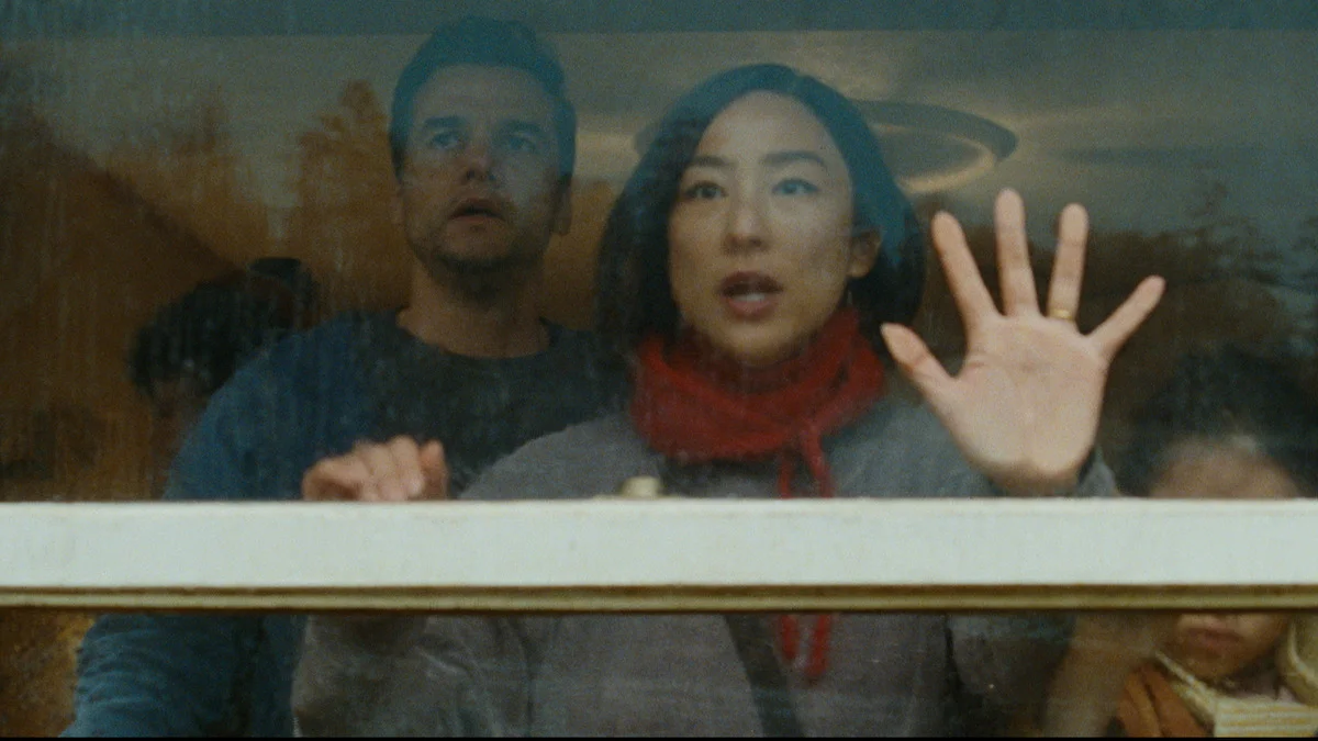 The Delgado family looking through a rain-covered window in The Last House