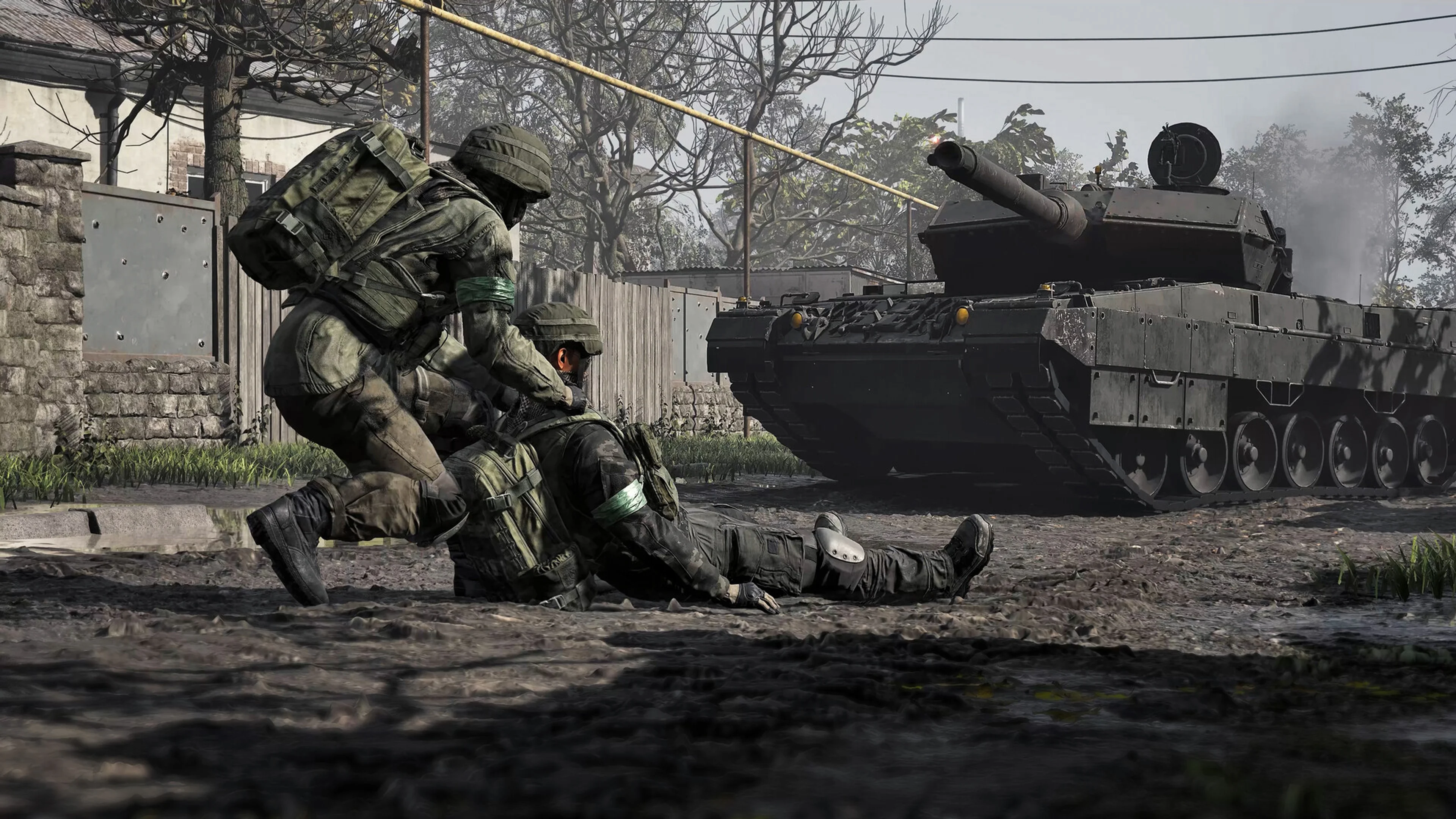 A WARDOGS soldier kneels beside a wounded teammate while a tank passes nearby.