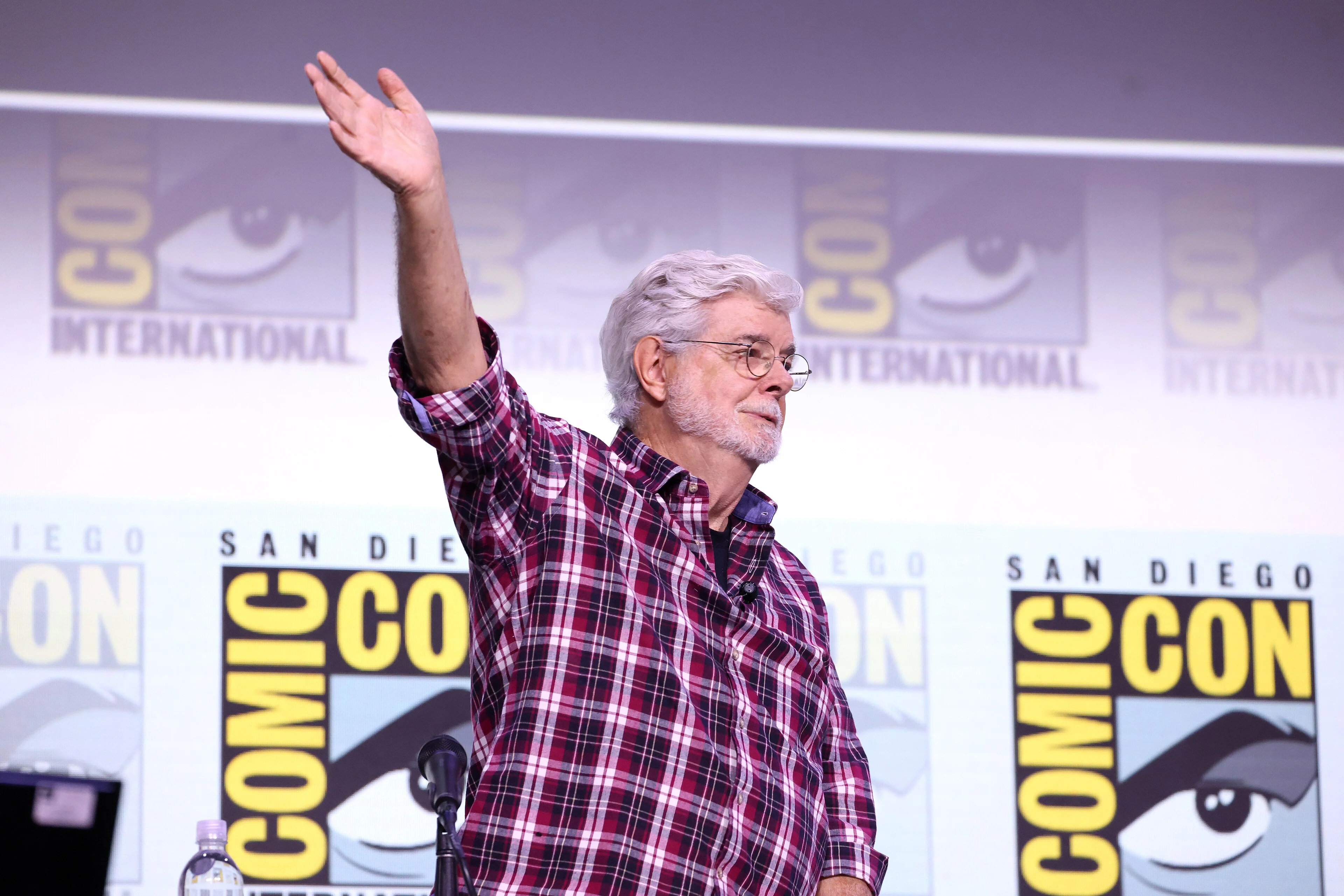 George Lucas waves while speaking at a 2025 panel for the Lucas Museum of Narrative Art.