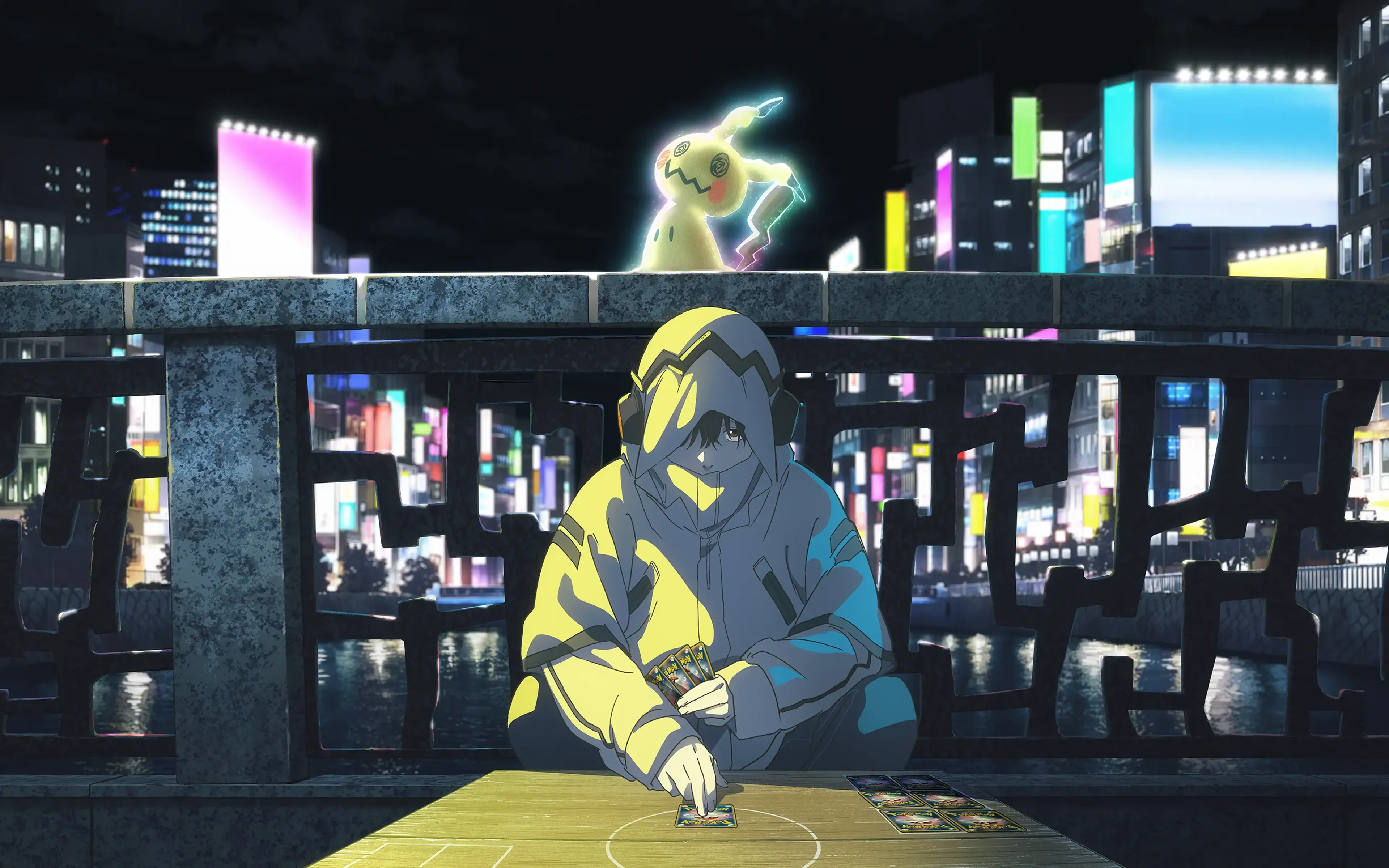 A hooded Pokémon Trading Card Game player sits at a city table while a glowing Mimikyu stands above them