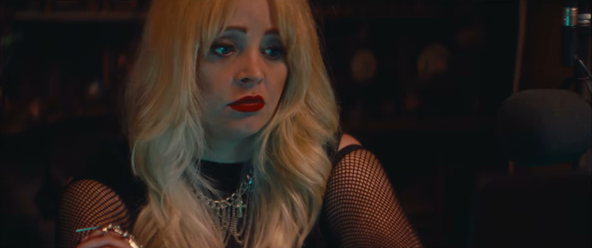 Jessica Dawn Willis at a microphone in Marrow, wearing blonde hair and red lipstick.