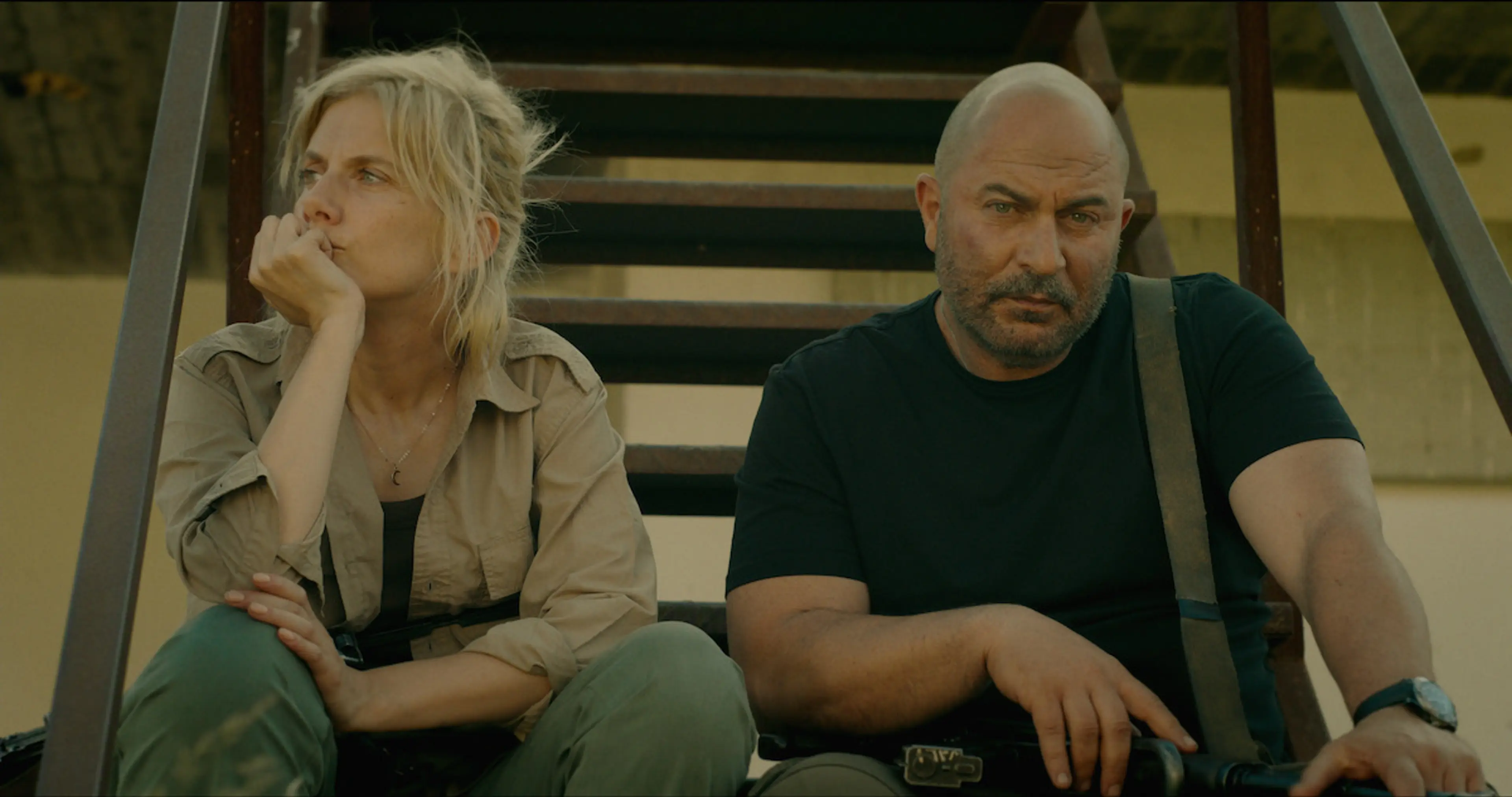 Anne and Doron sit on outdoor metal stairs in Fauda Season 5.