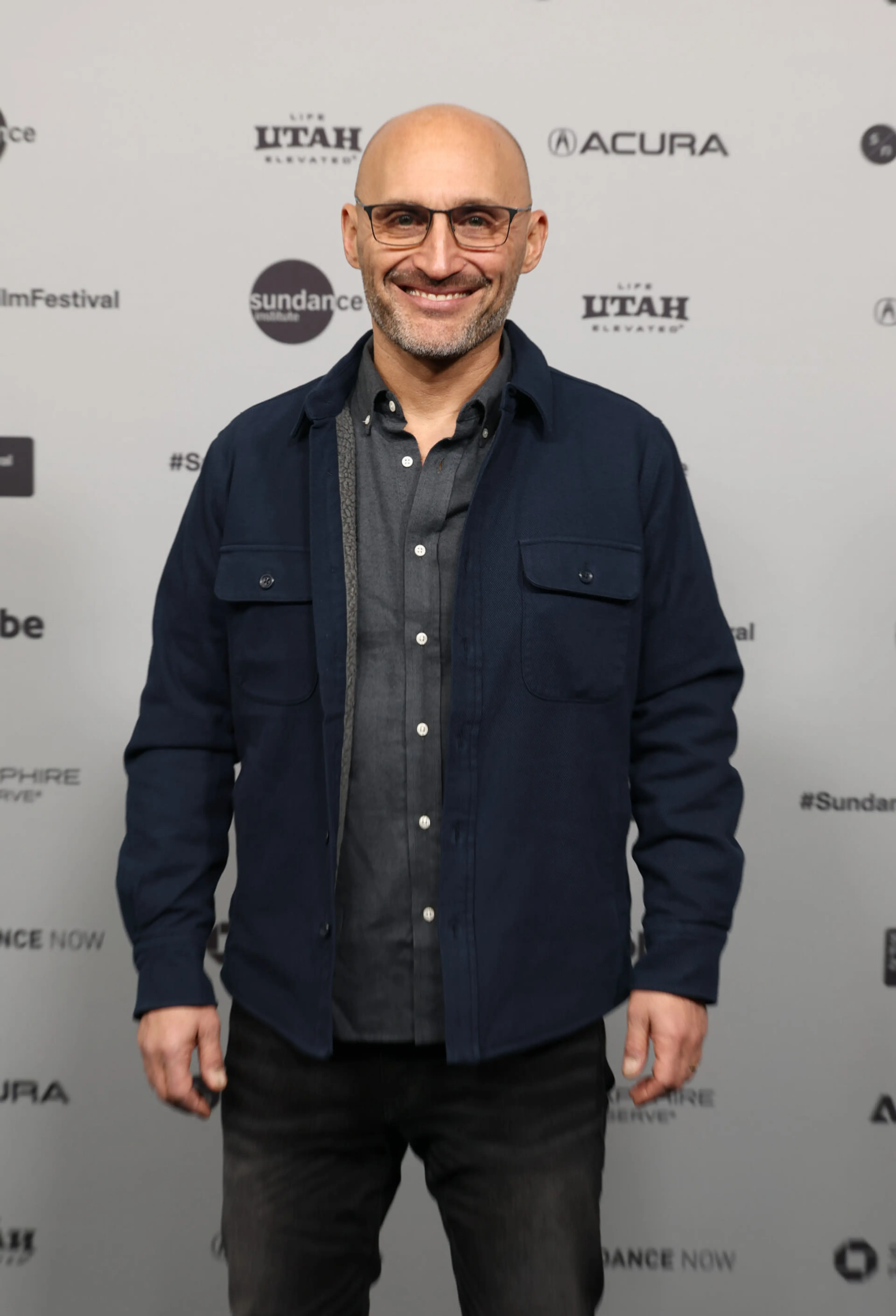 Director Amir Bar-Lev smiles at the Sundance premiere in glasses and a dark shirt.