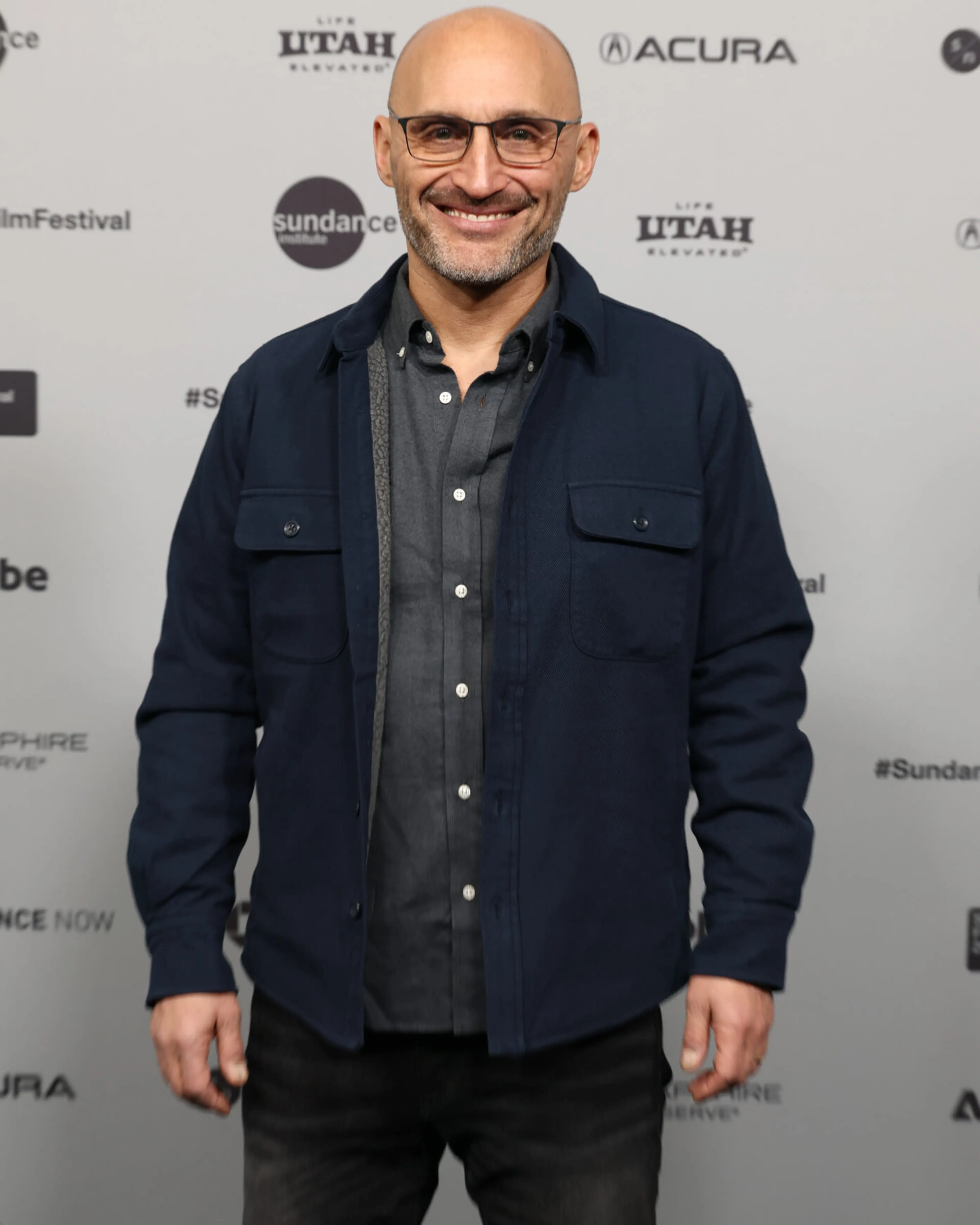 Director Amir Bar-Lev smiles at the Sundance premiere in glasses and a dark shirt.