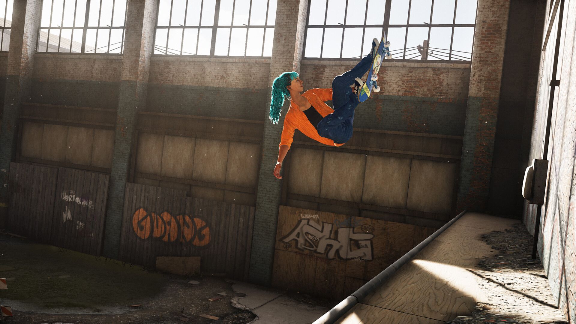 A skater performs an airborne grab inside a warehouse with tall windows and metal beams.