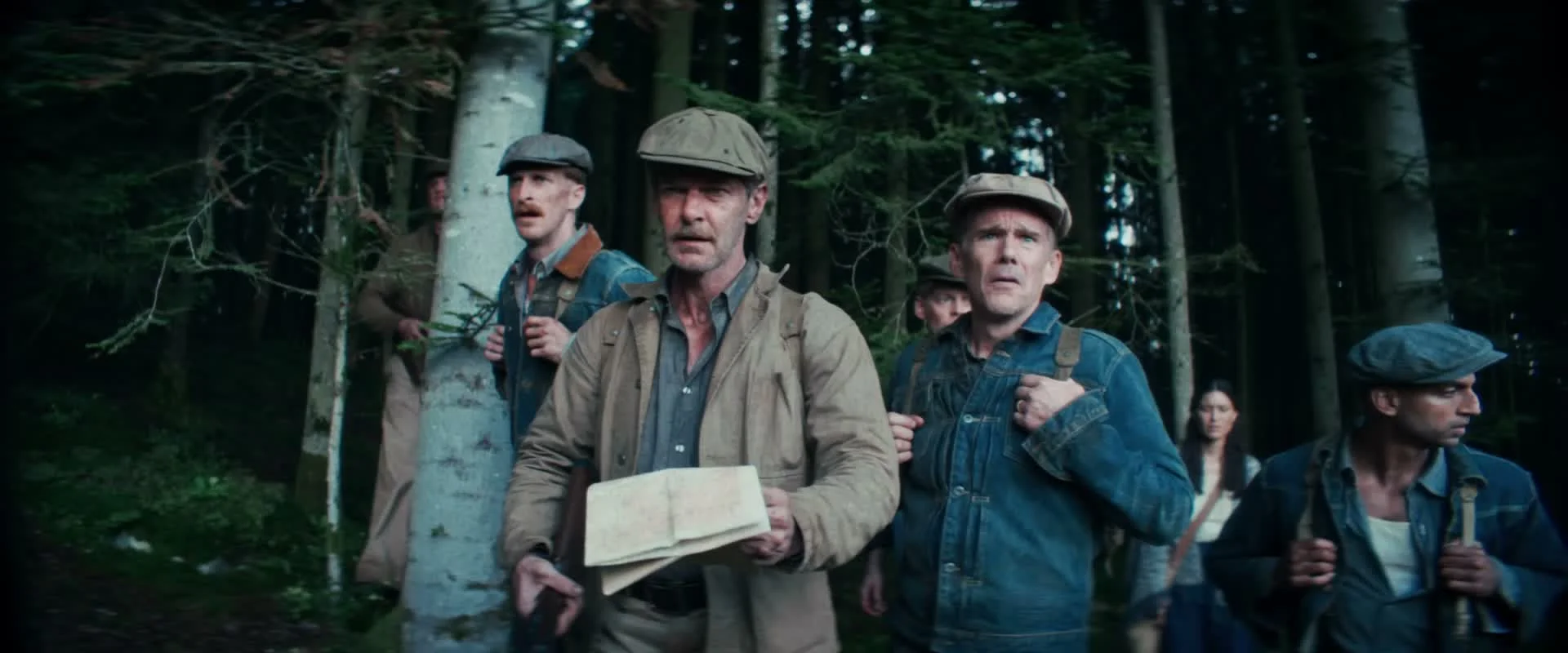 The group stands among trees with backpacks while one man holds an unfolded map.