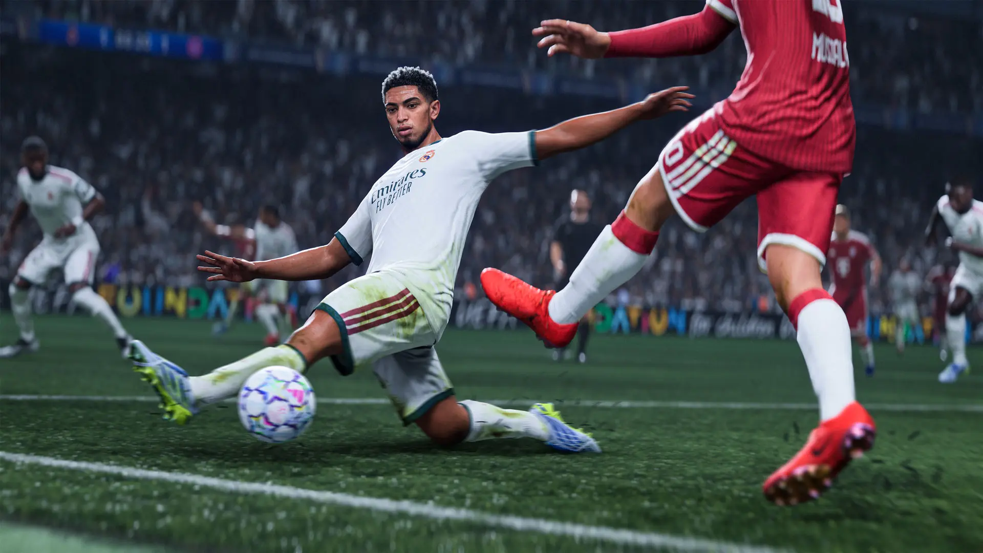 Jude Bellingham slides toward the ball as a Bayern player in red tries to reach it.