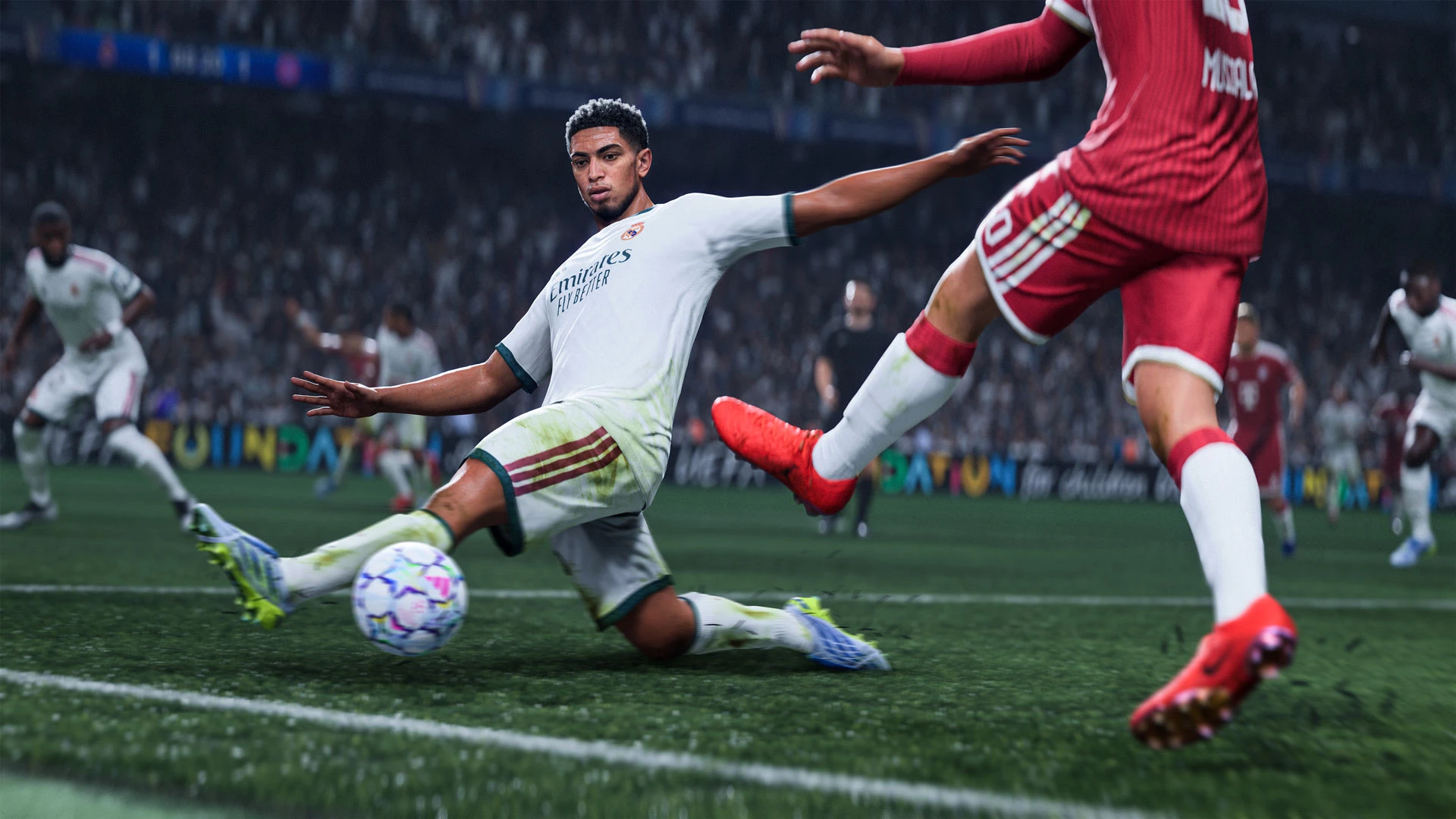 Jude Bellingham slides toward the ball as a Bayern player in red tries to reach it.
