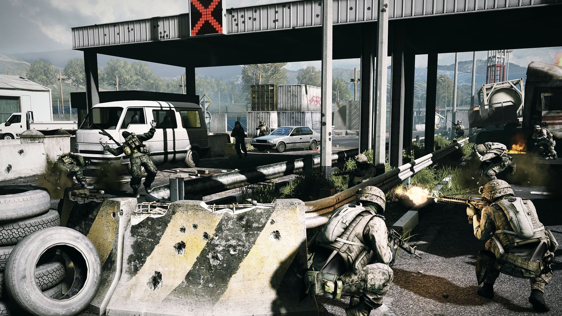 Soldiers take cover among concrete barriers, tires and abandoned vehicles at a checkpoint.