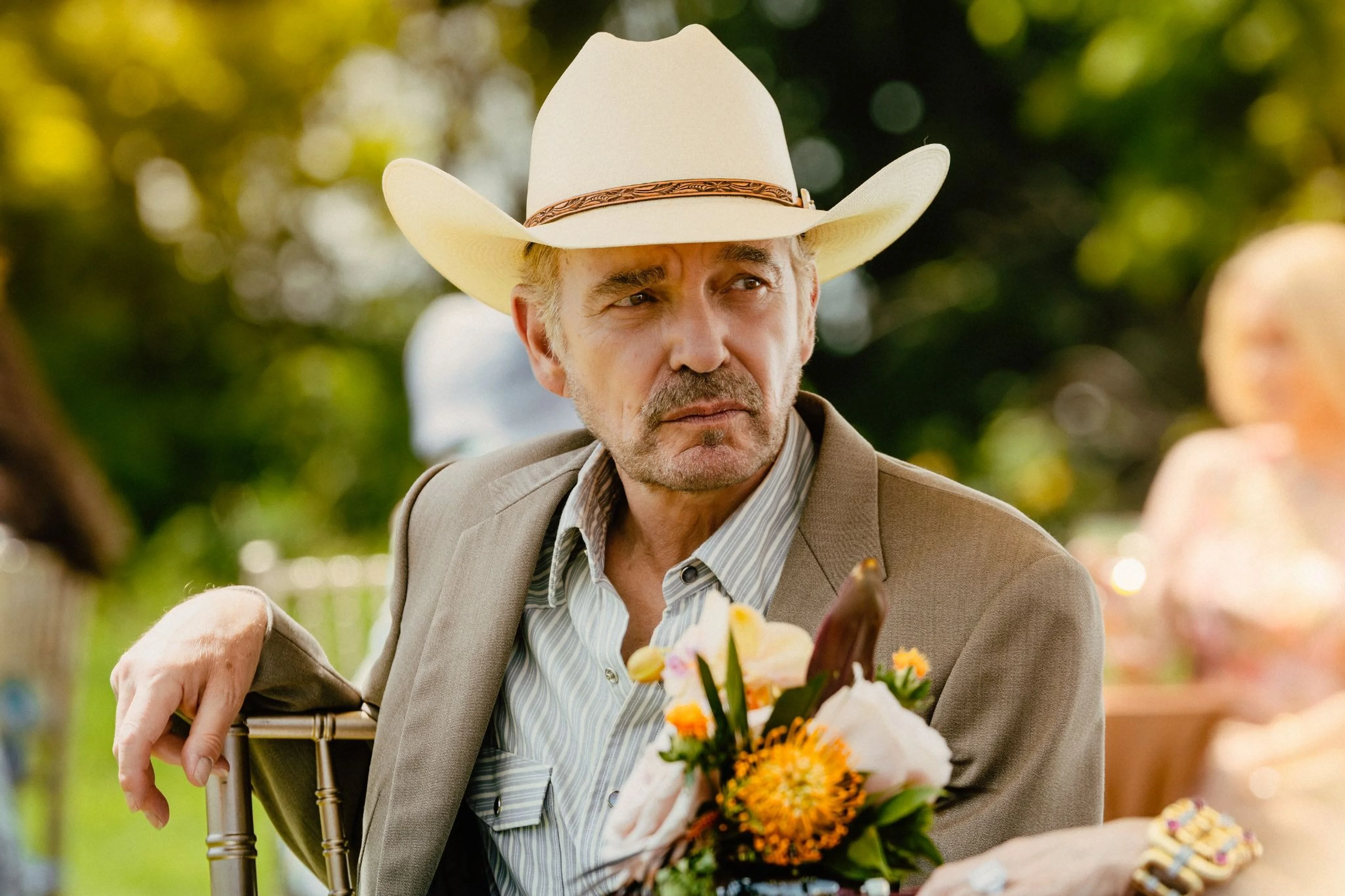 Billy Bob Thornton as Tommy Norris sits outdoors wearing a white cowboy hat in Landman.