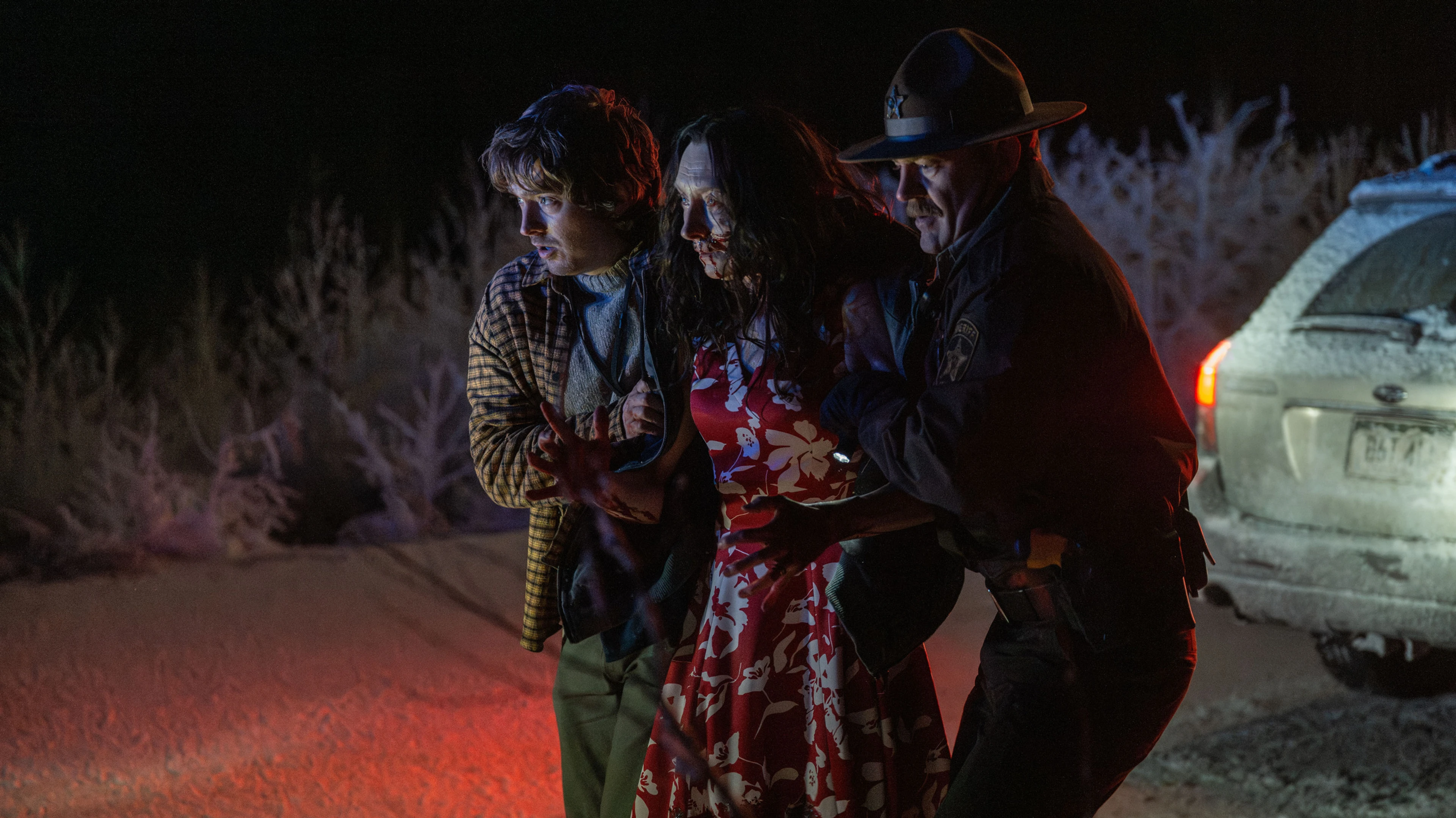 Austin Abrams as Bryan helps an injured woman beside a police officer in Resident Evil.