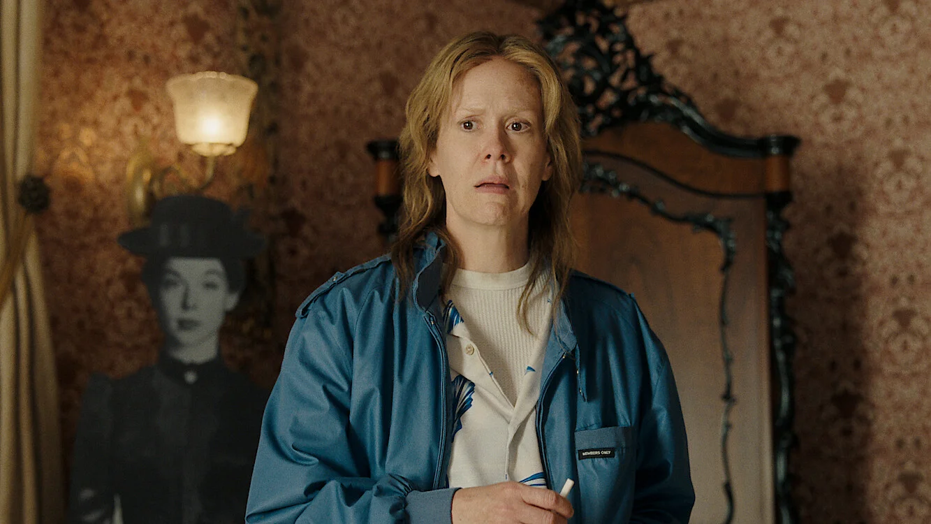 Sarah Paulson stands in a vintage room wearing a blue jacket.