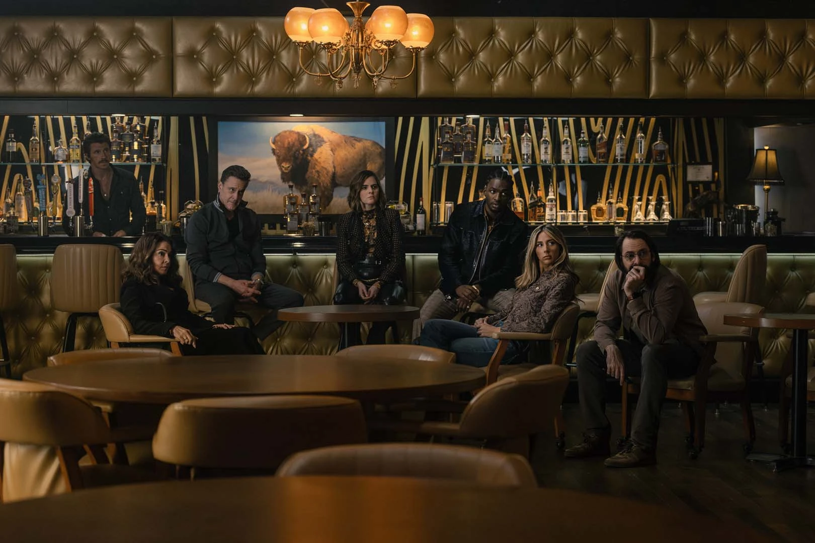 Garrett Hedlund, Annabella Sciorra, Chris Caldovino, McKenna Quigley Harrington, Jay Will, Scarlet Stallone, and Martin Starr gather in a bar in Tulsa King Season 4.