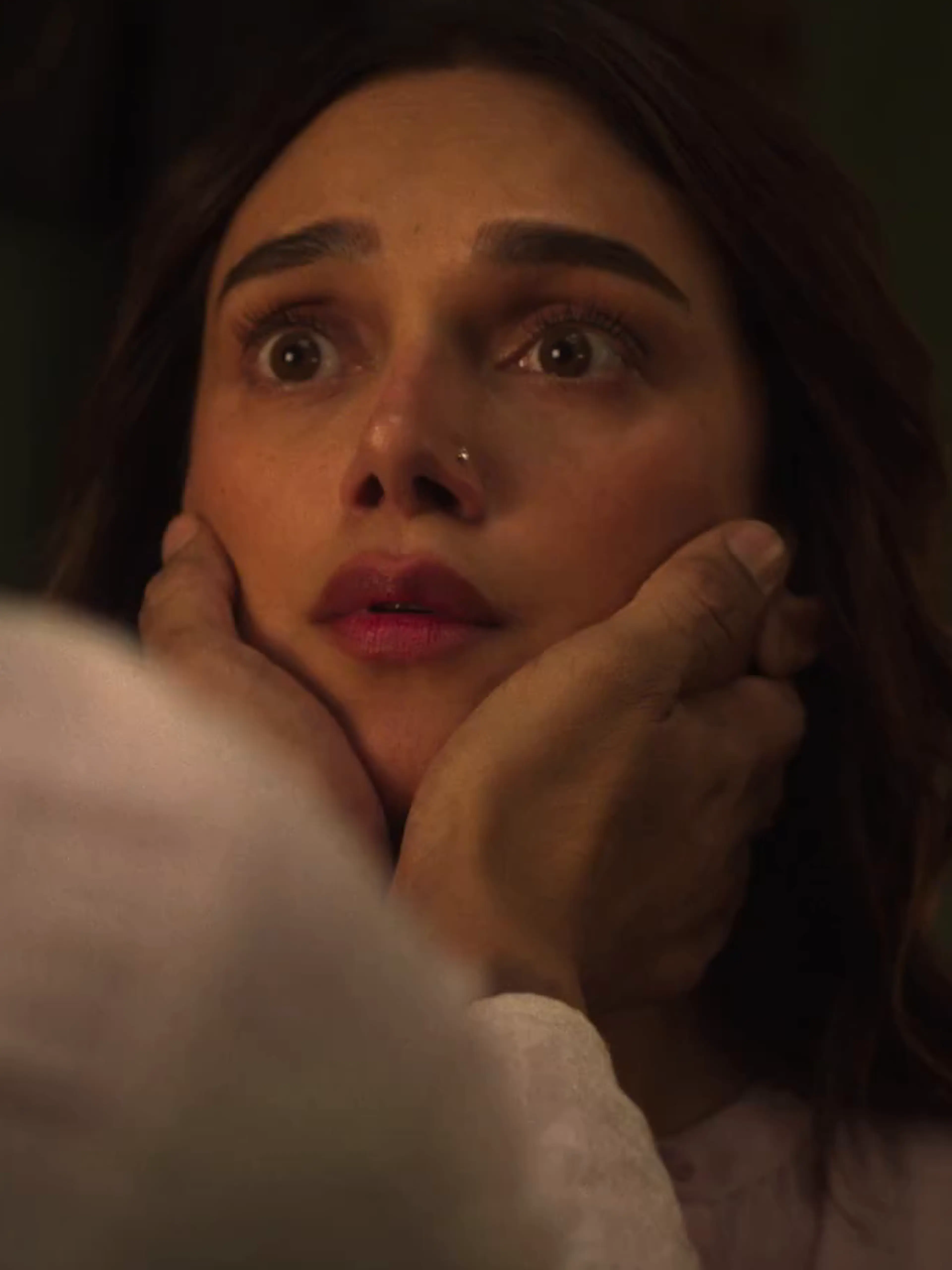 A woman looks upward while another character holds her face in a close-up from the official Lust Stories 3 trailer.