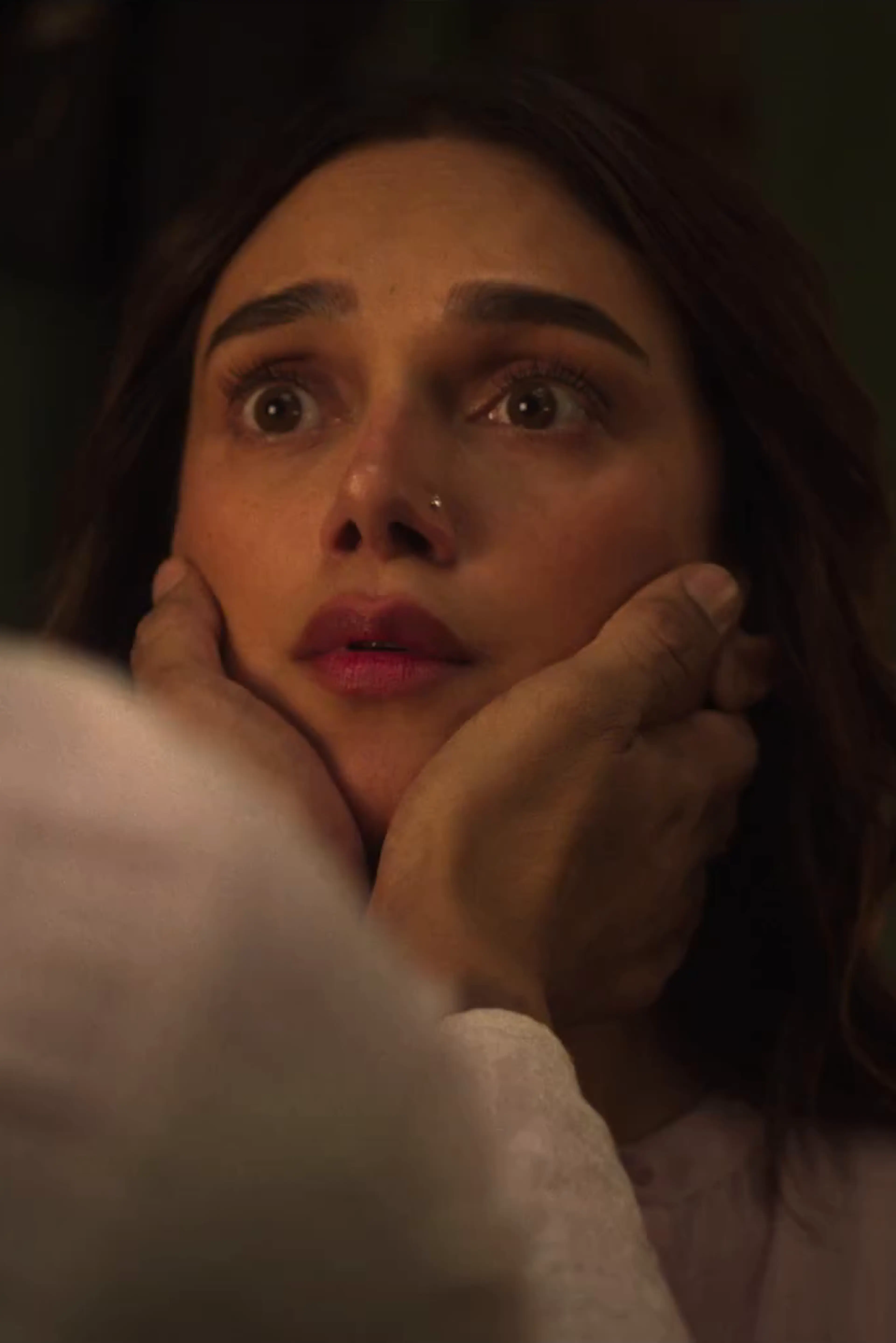 A woman looks upward while another character holds her face in a close-up from the official Lust Stories 3 trailer.