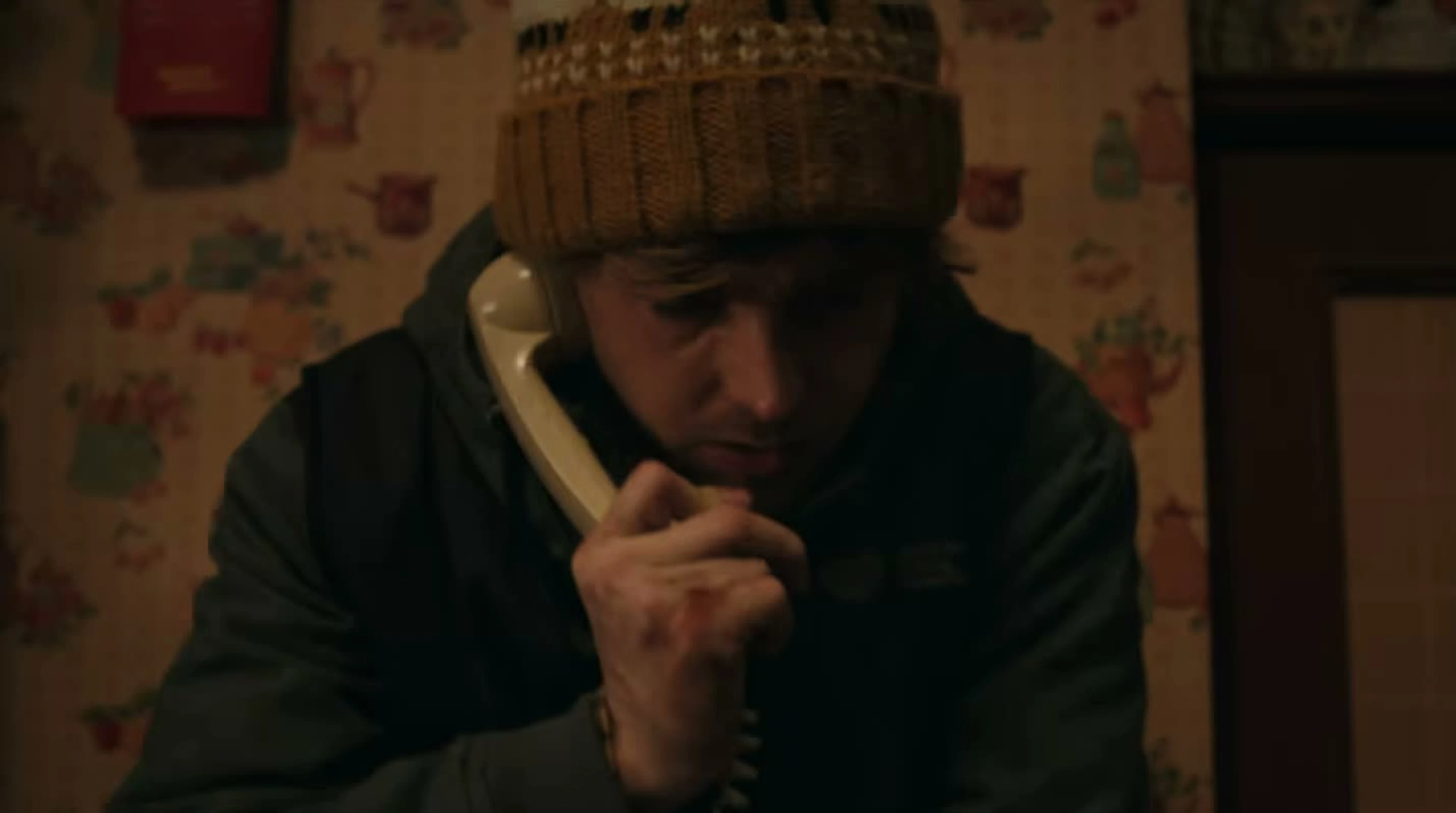 Austin Abrams as Bryan listens intently on a telephone in Resident Evil.