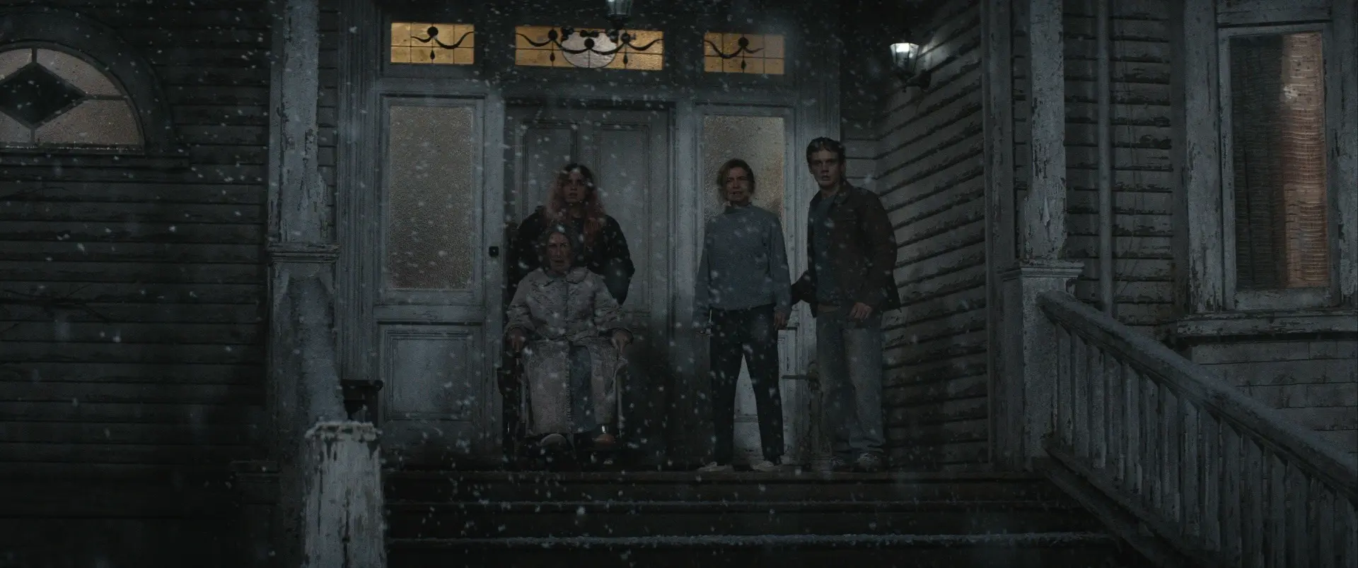 Three people stand at the entrance of the weathered family house in Evil Dead Burn.
