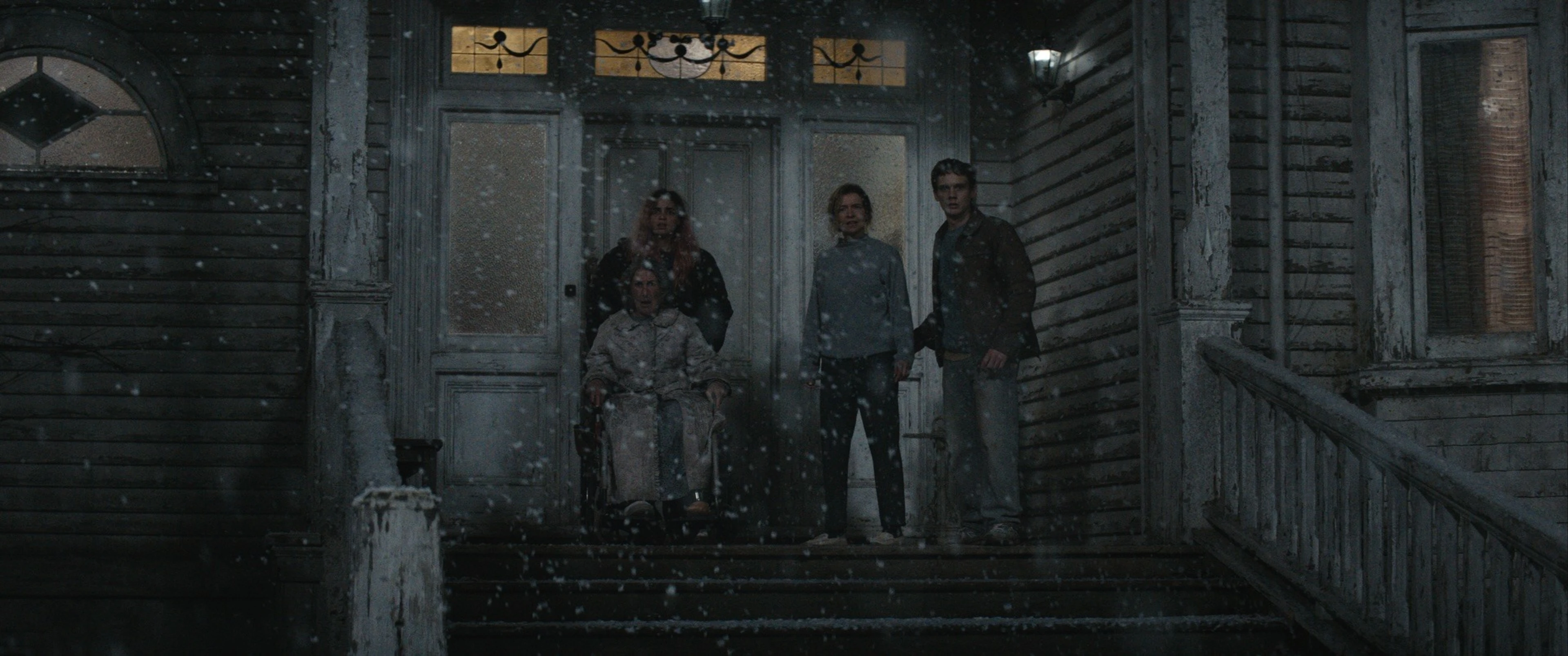 Three people stand at the entrance of the weathered family house in Evil Dead Burn.