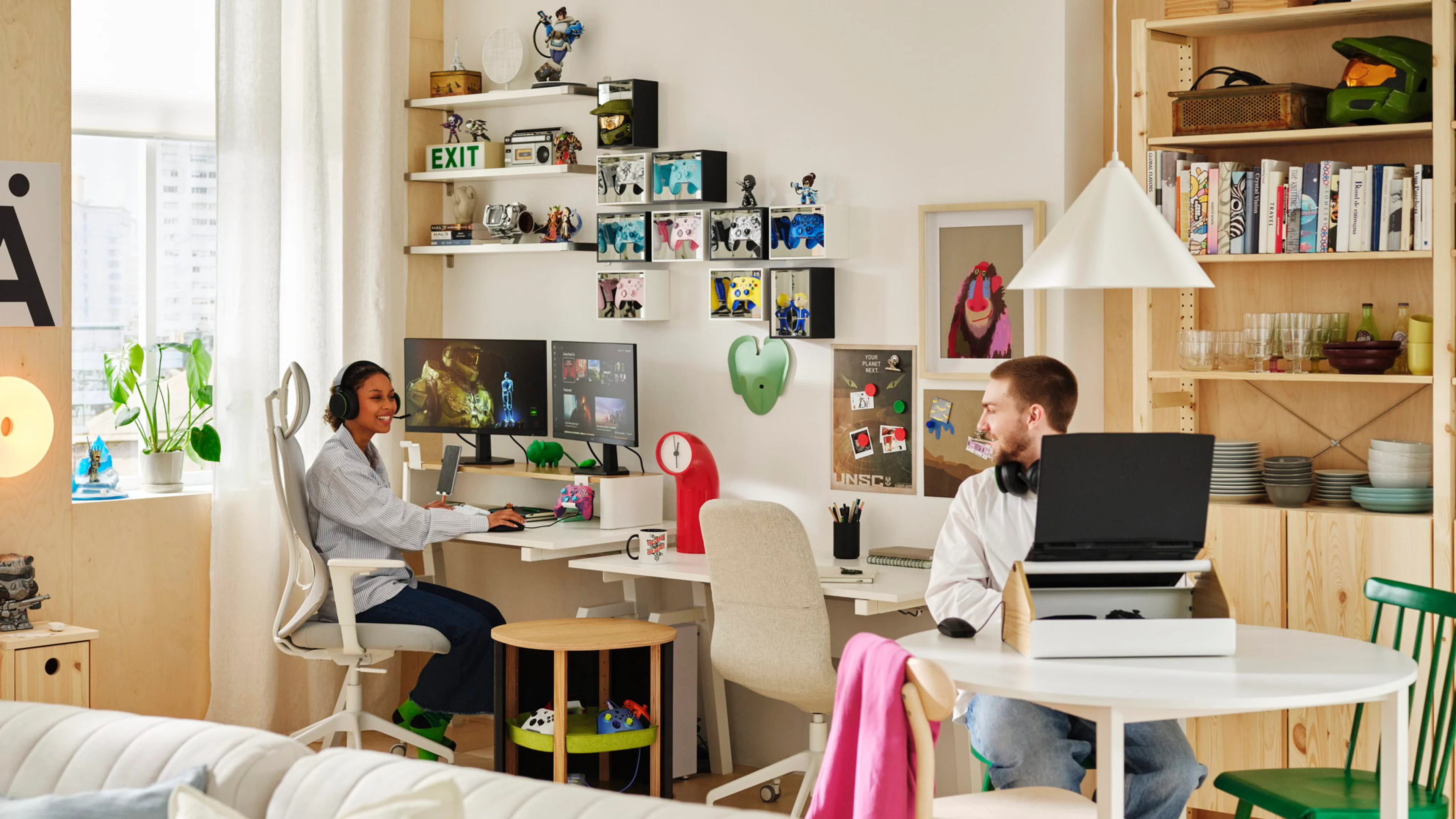 Two people use separate computer setups in a shared room furnished with YXSTABY gaming pieces.