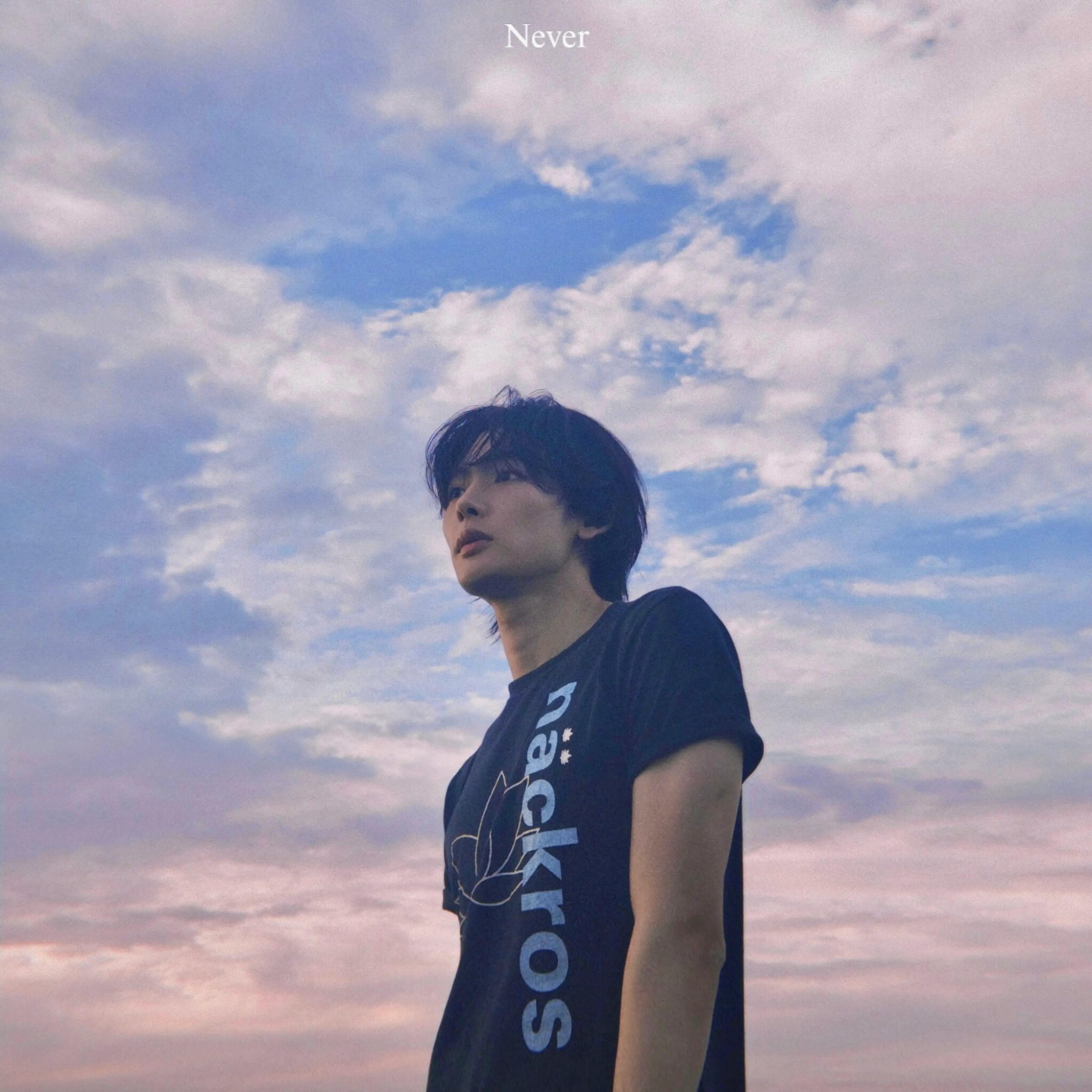 NOA looks upward beneath a cloudy sky on the “Never” single cover.