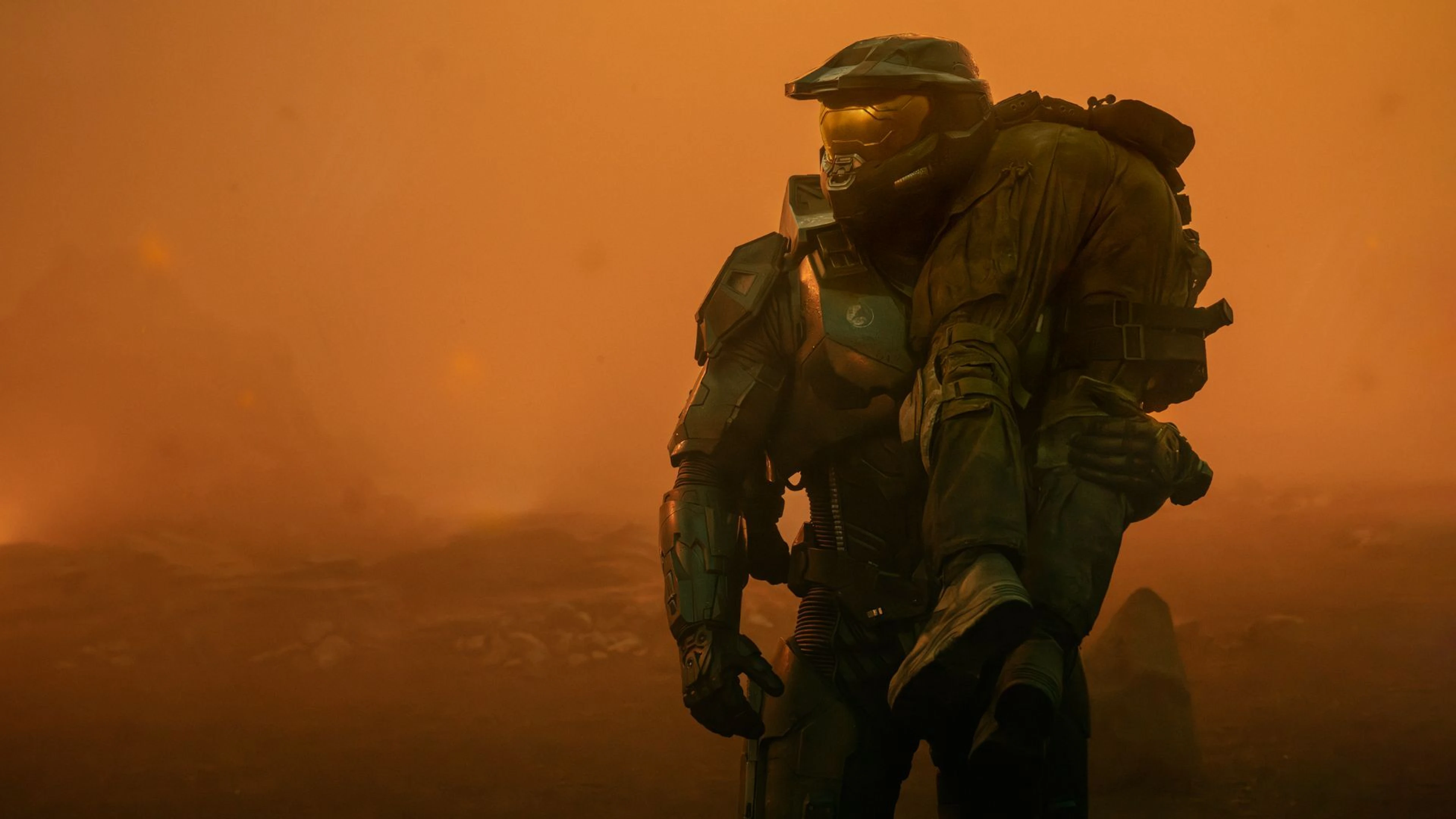 Master Chief from Halo stands in an orange, smoky landscape.