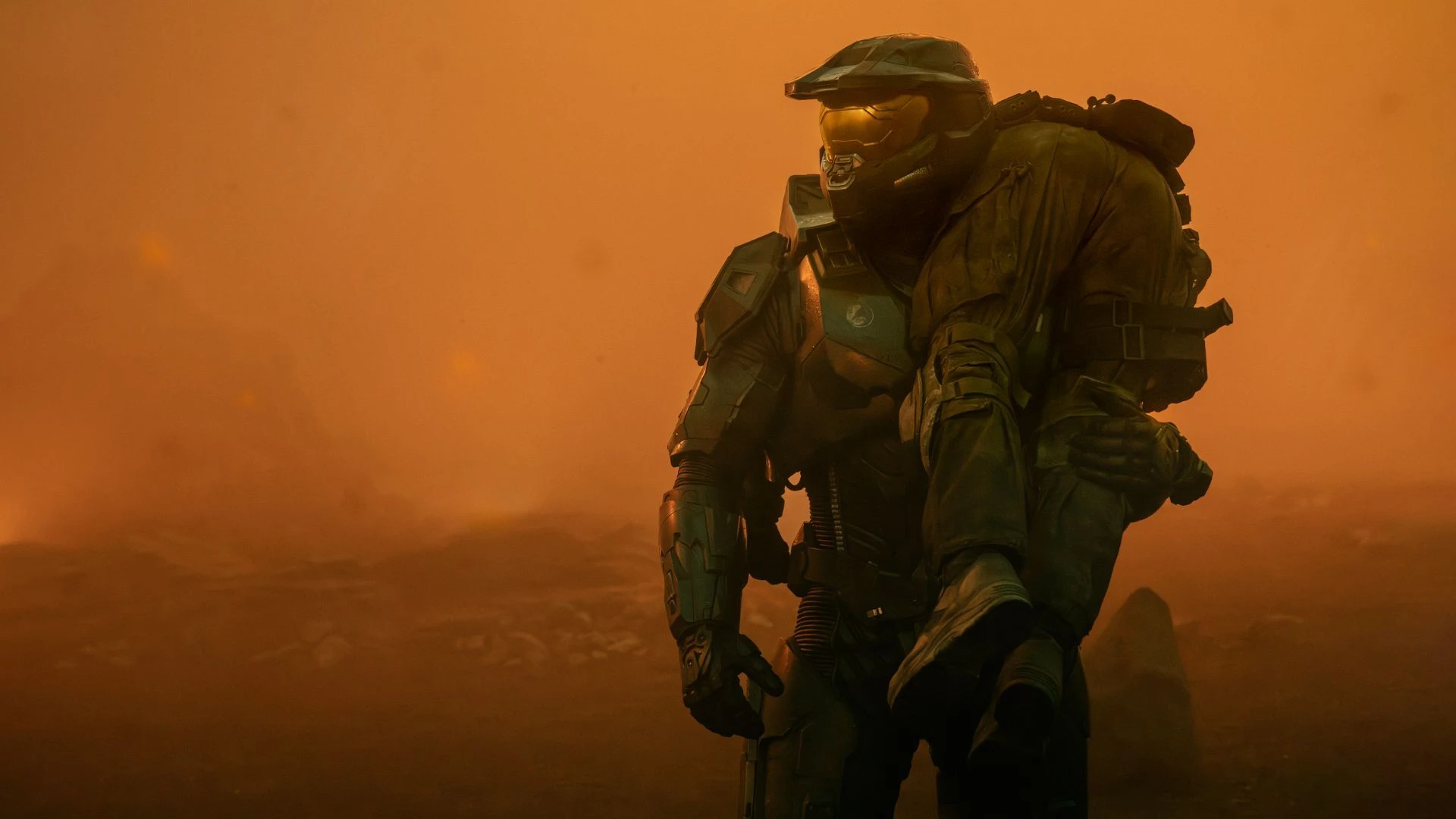 Master Chief from Halo stands in an orange, smoky landscape.