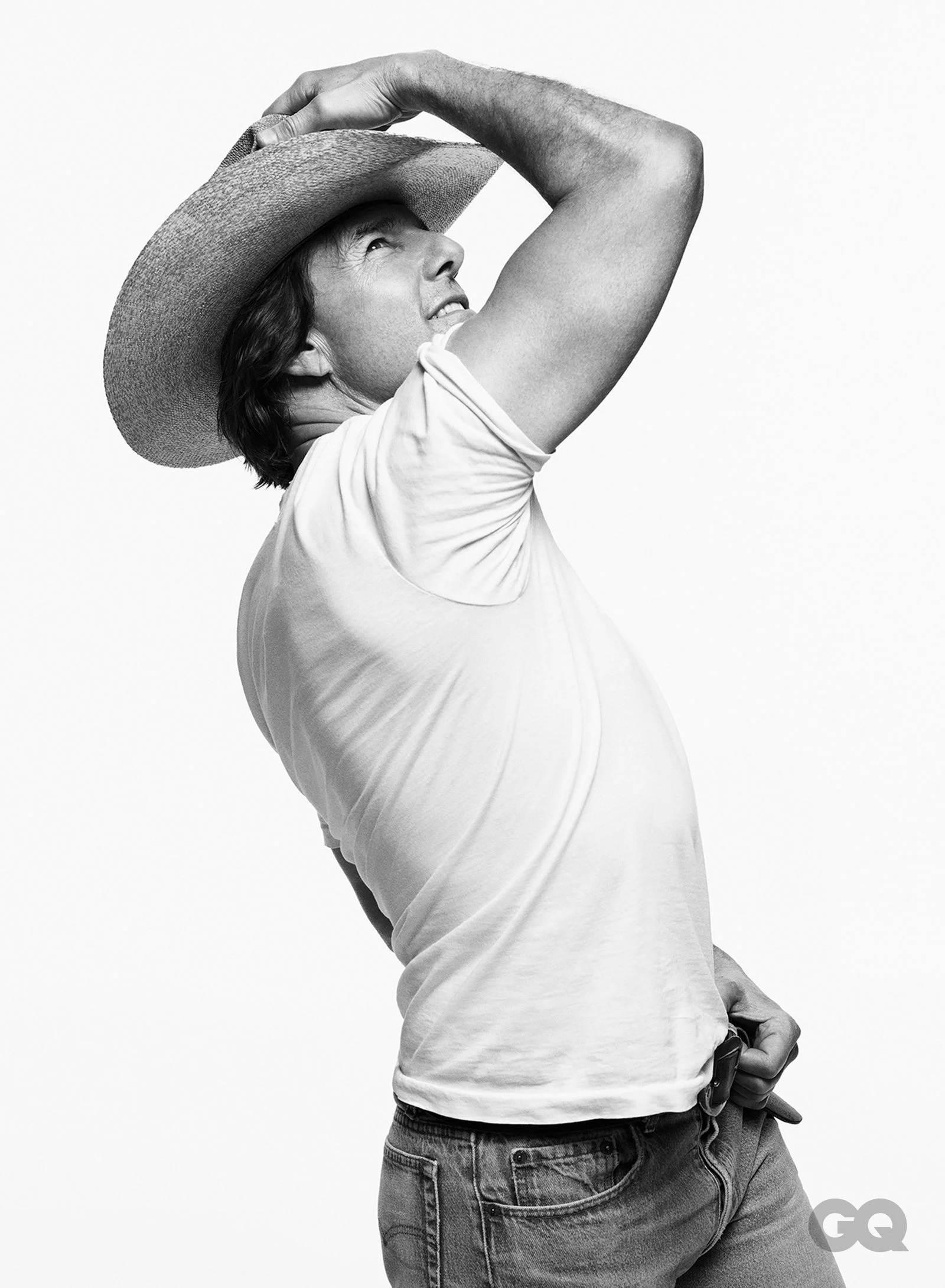 Black-and-white portrait of Tom Cruise in a cowboy hat and white shirt, looking upward.