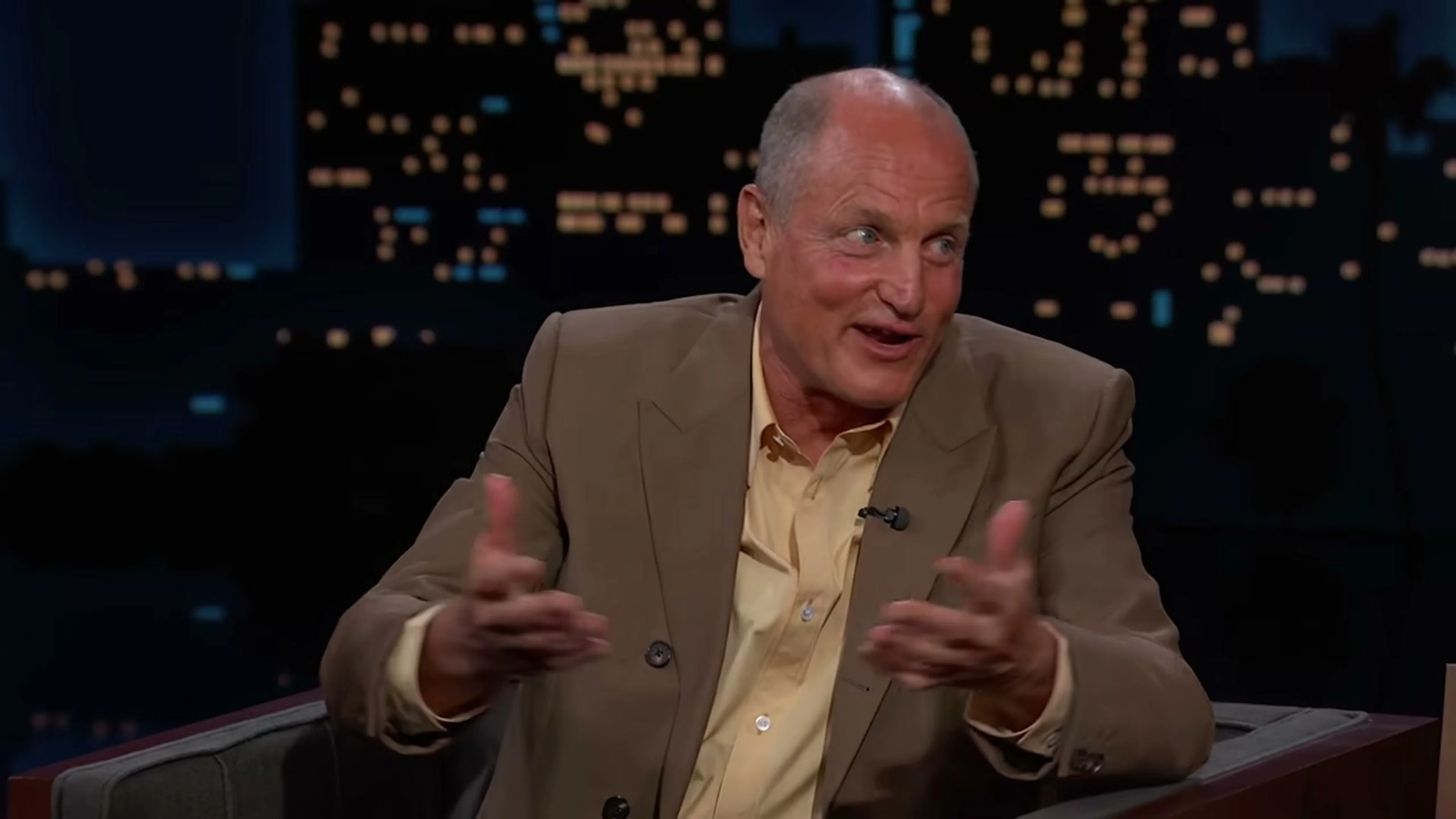 Woody Harrelson gestures with one hand while answering Jimmy Kimmel.