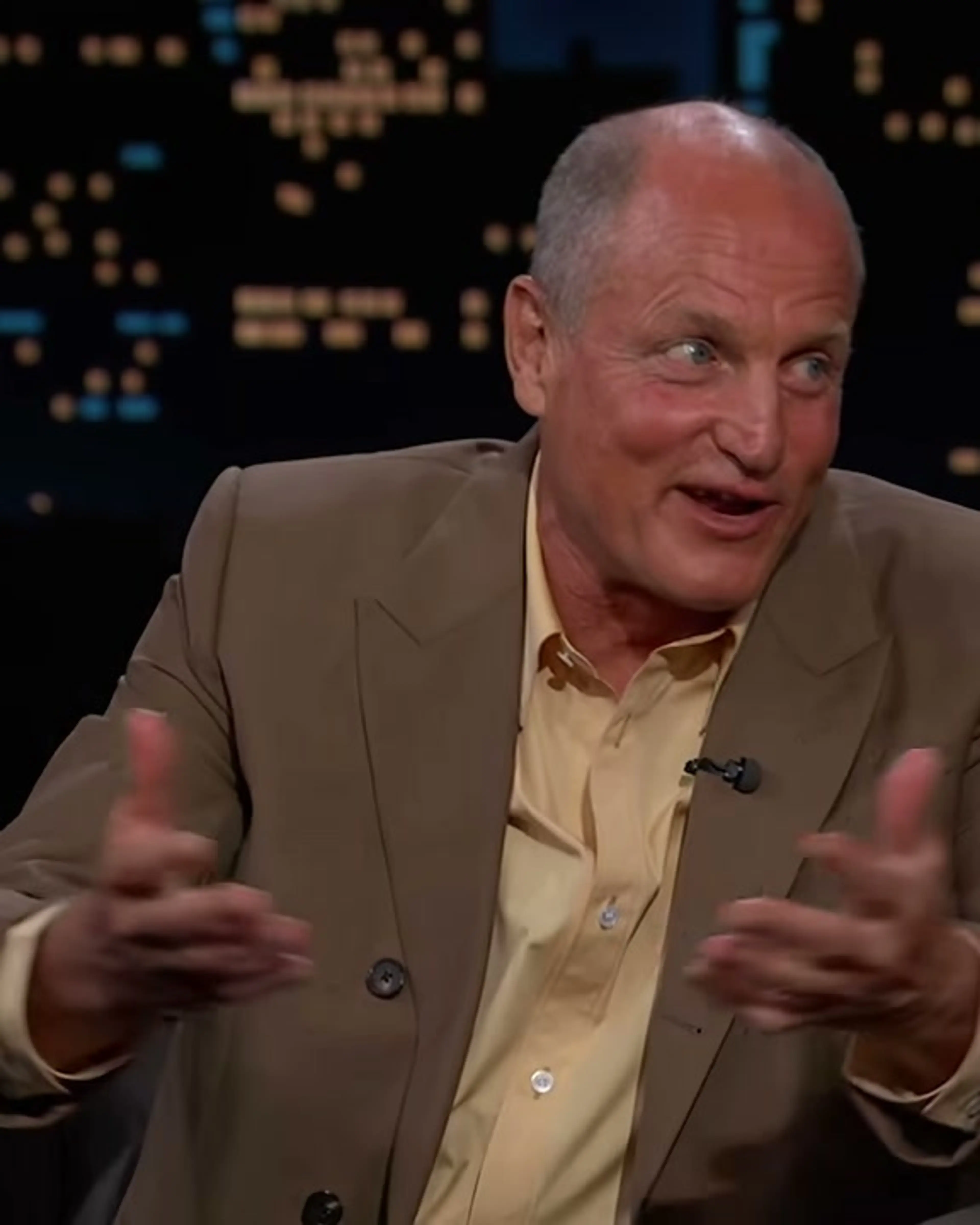 Woody Harrelson gestures with one hand while answering Jimmy Kimmel.