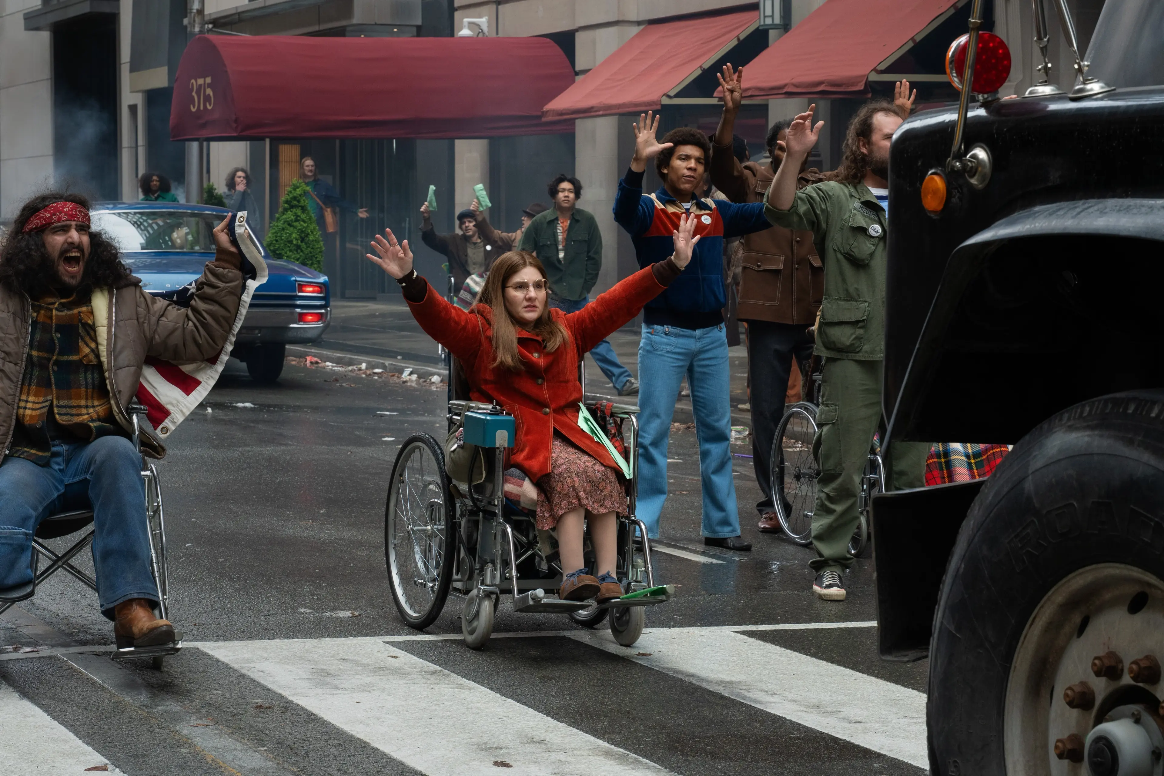 Ruth Madeley as Judy Heumann and fellow protesters in wheelchairs move into a city street in Being Heumann.