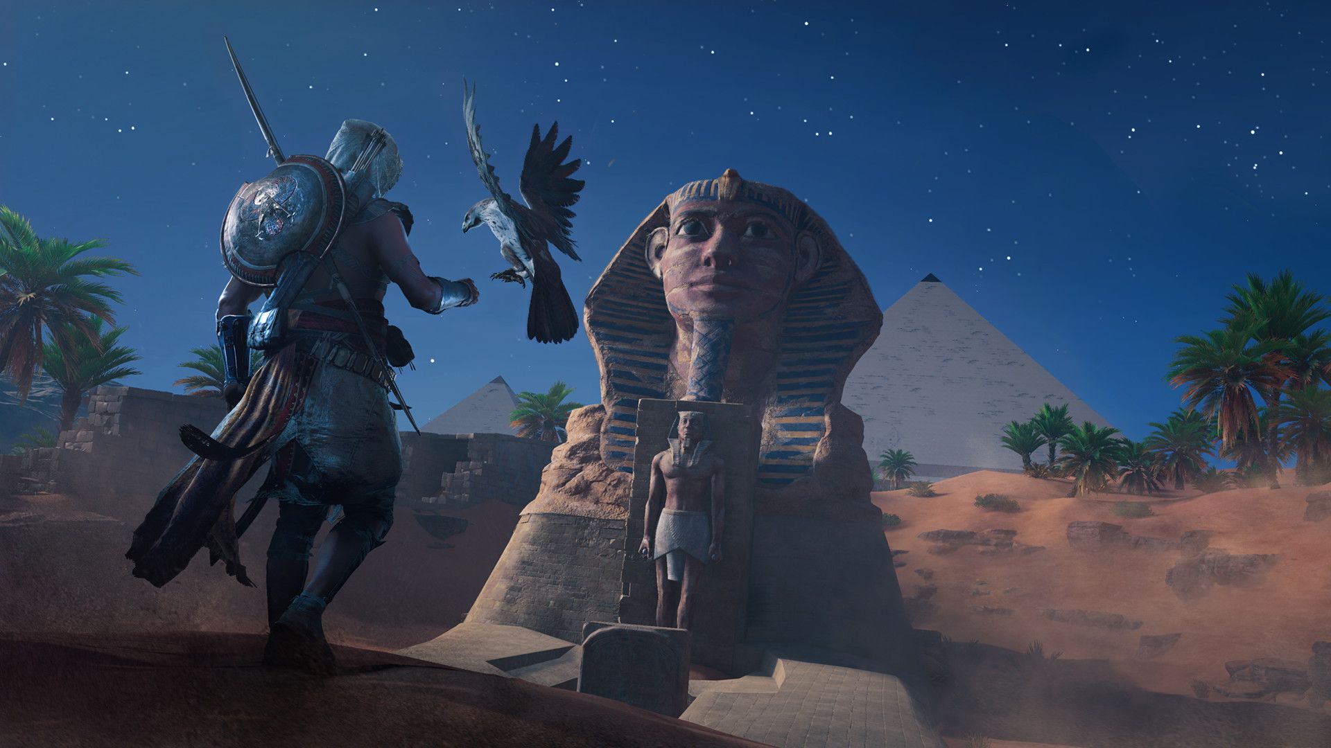 Bayek stands before a giant sphinx at night.