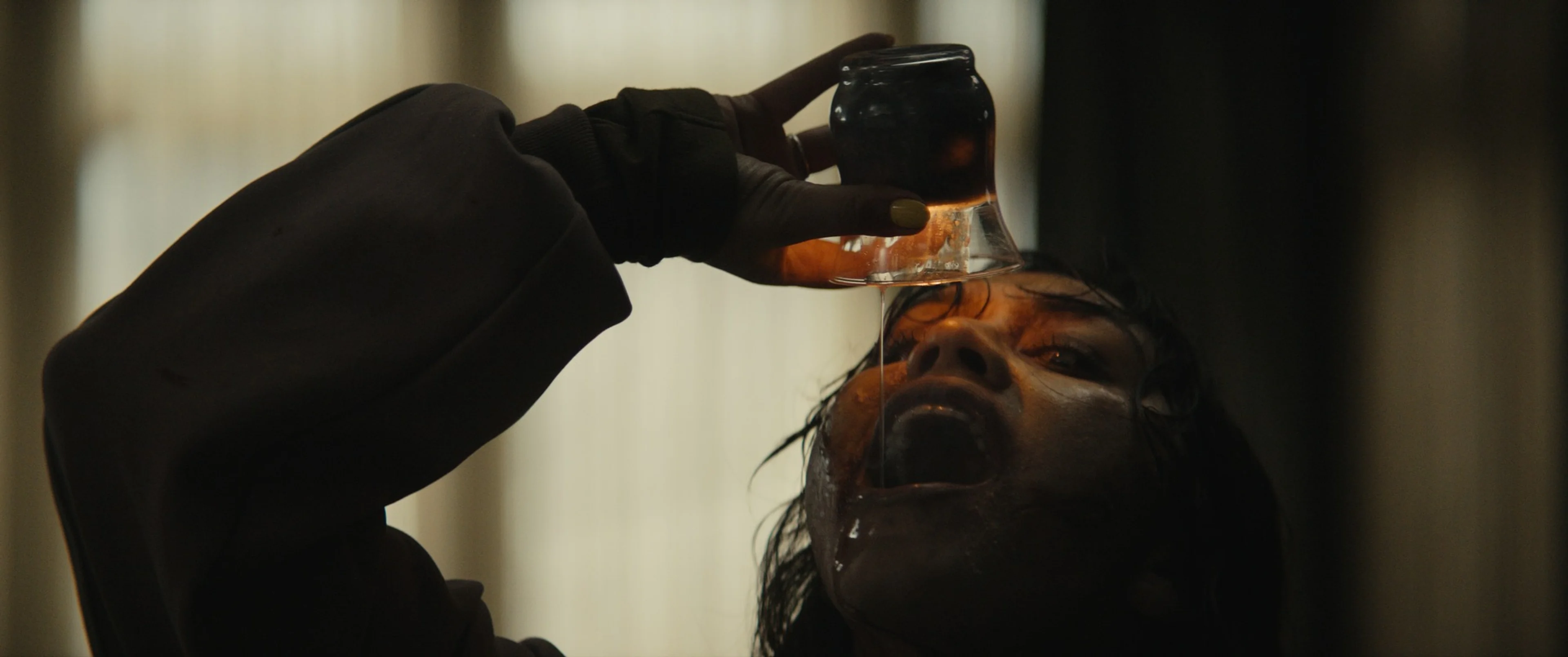 The possessed Thya tips a bottle over her face.