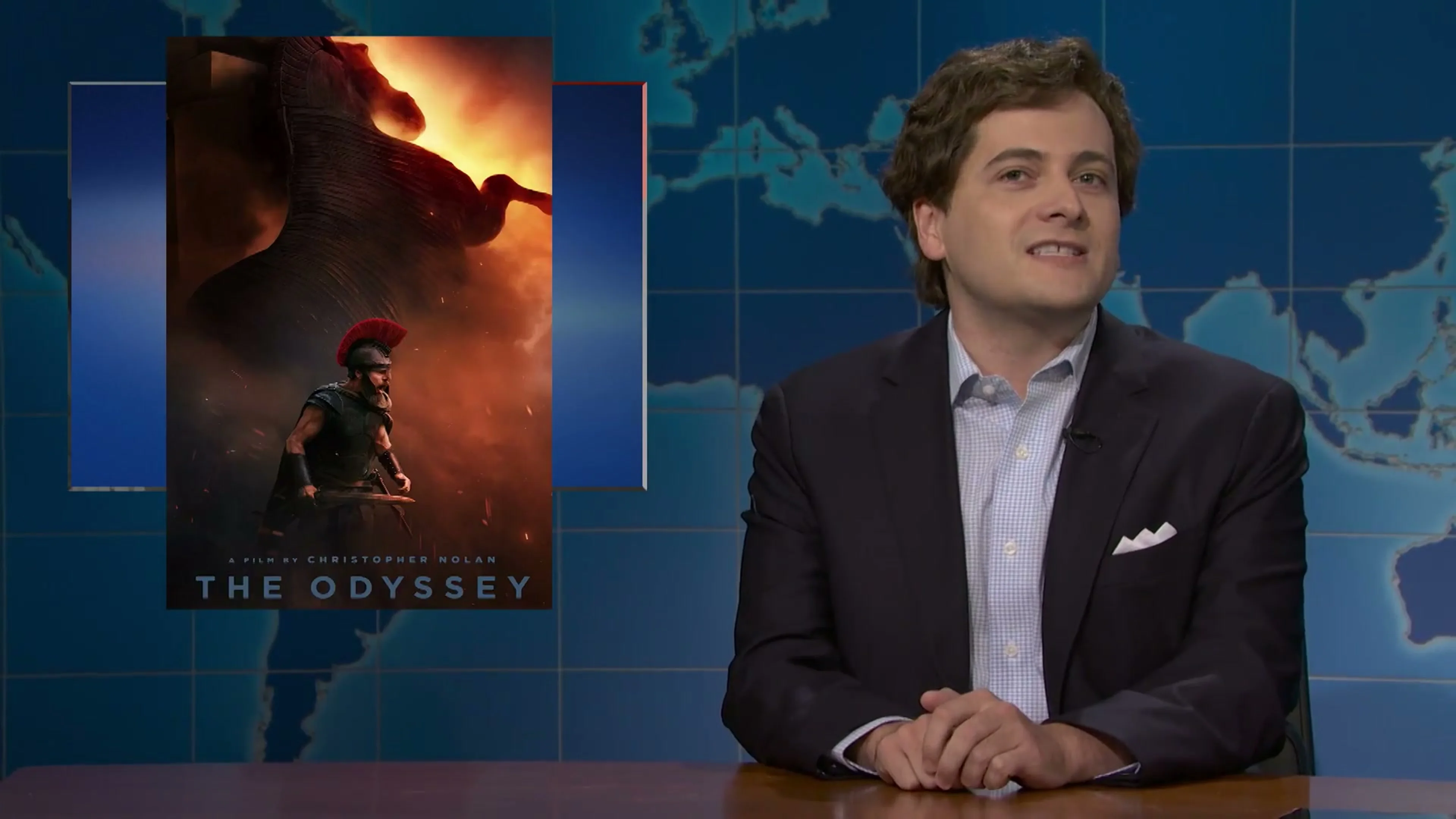 Jeremy Culhane as Tucker Carlson speaks beside The Odyssey poster on Saturday Night Live.