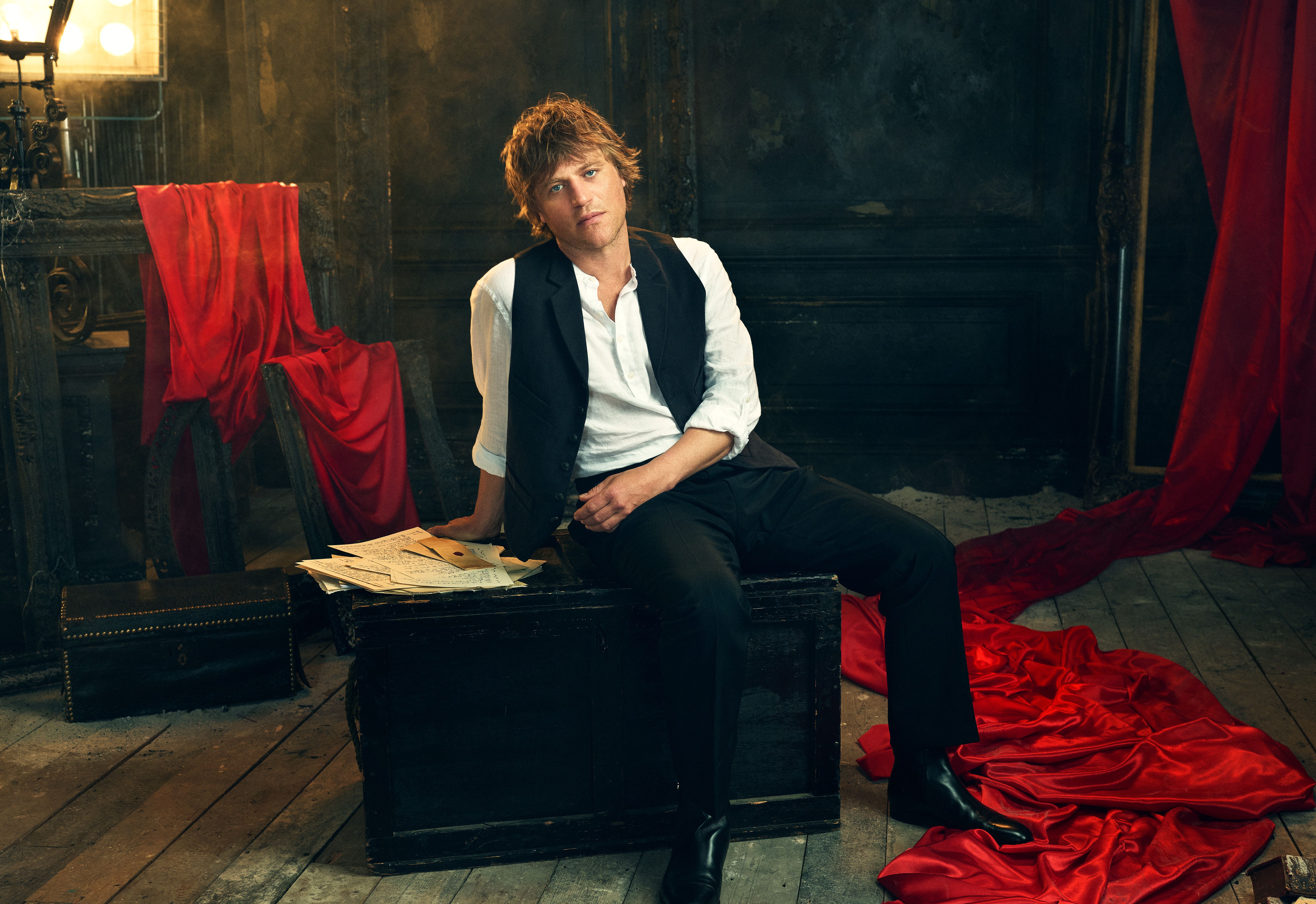 Johnny Flynn wears a white shirt and black waistcoat in an official Dracula audio-drama portrait.