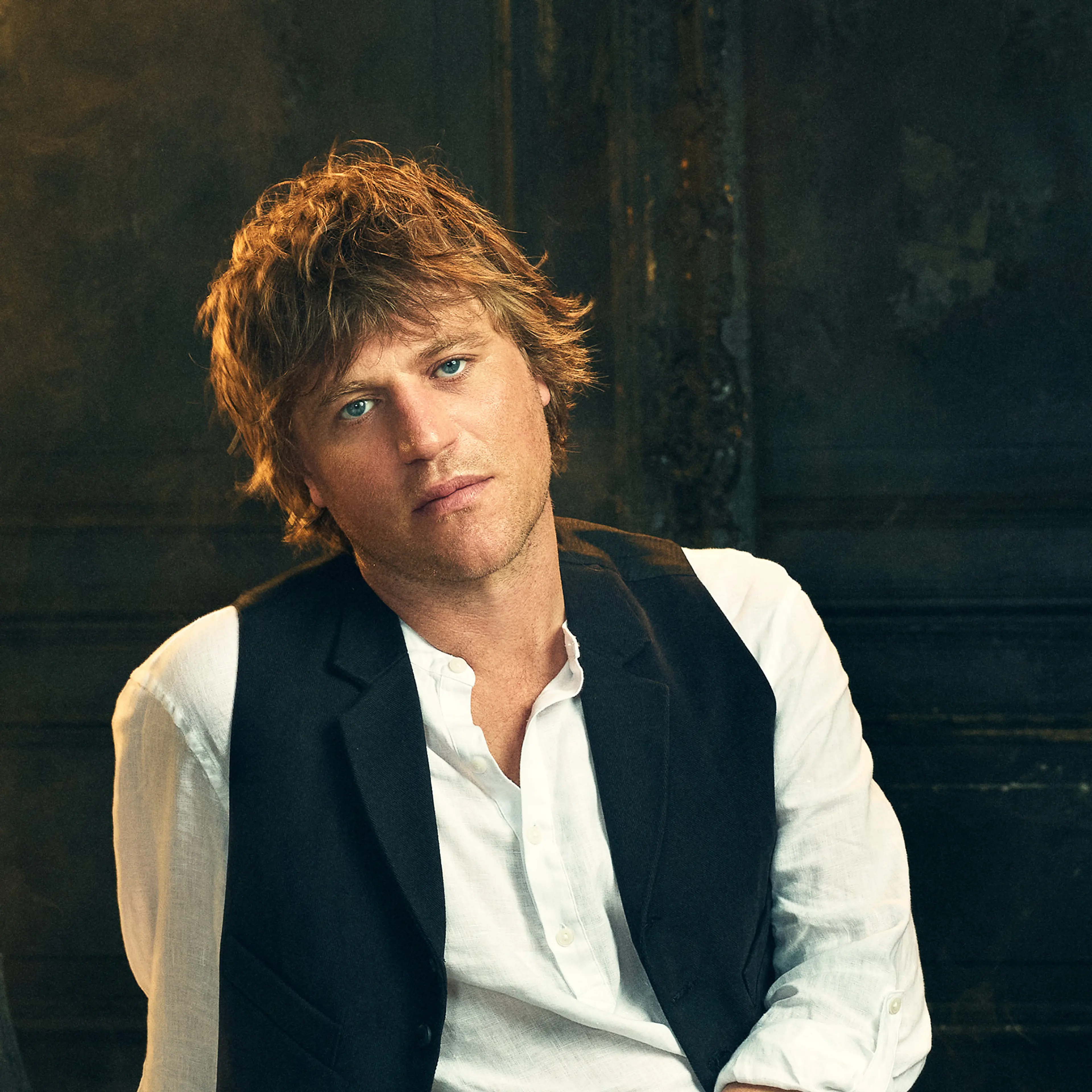 Johnny Flynn wears a white shirt and black waistcoat in an official Dracula audio-drama portrait.