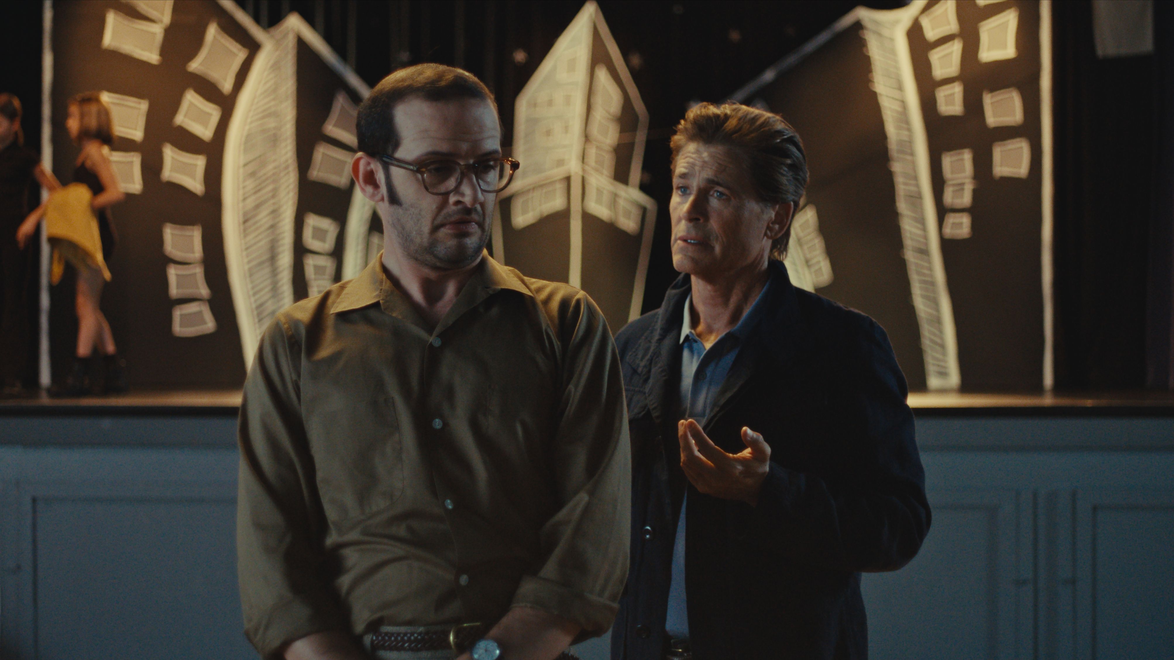 Will Brill and Rob Lowe stand together in front of a school stage in The Musical.