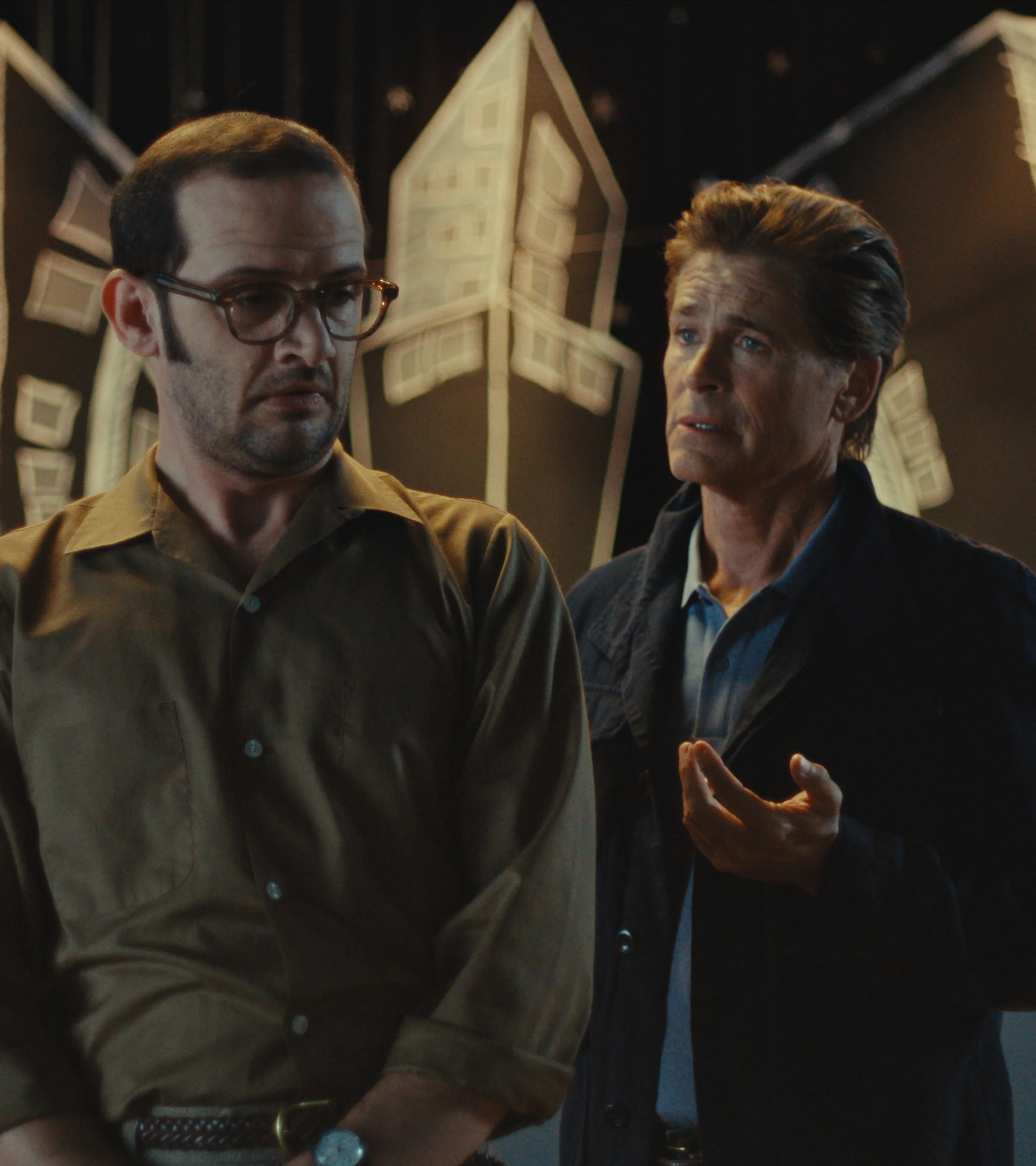 Will Brill and Rob Lowe stand together in front of a school stage in The Musical.