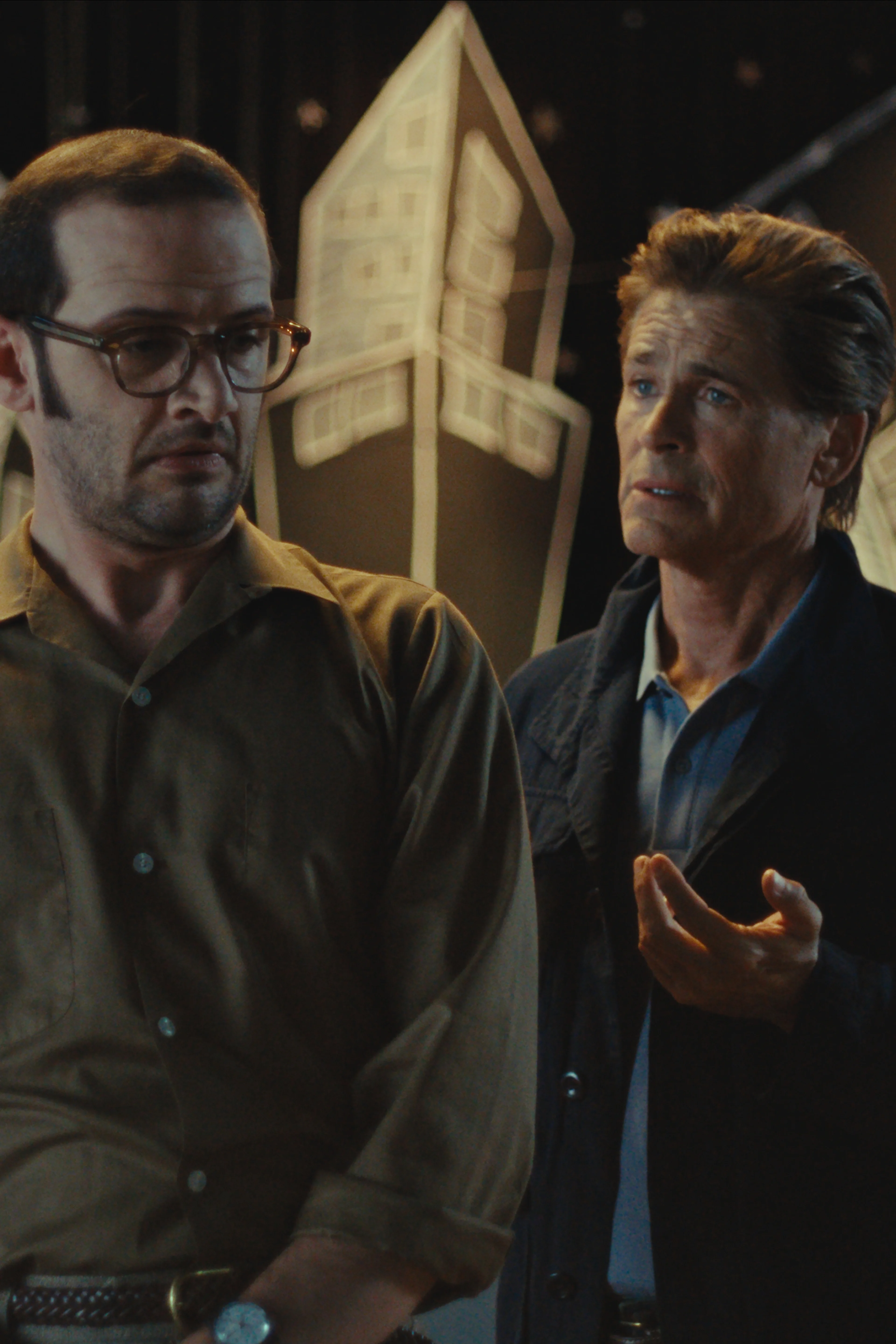 Will Brill and Rob Lowe stand together in front of a school stage in The Musical.