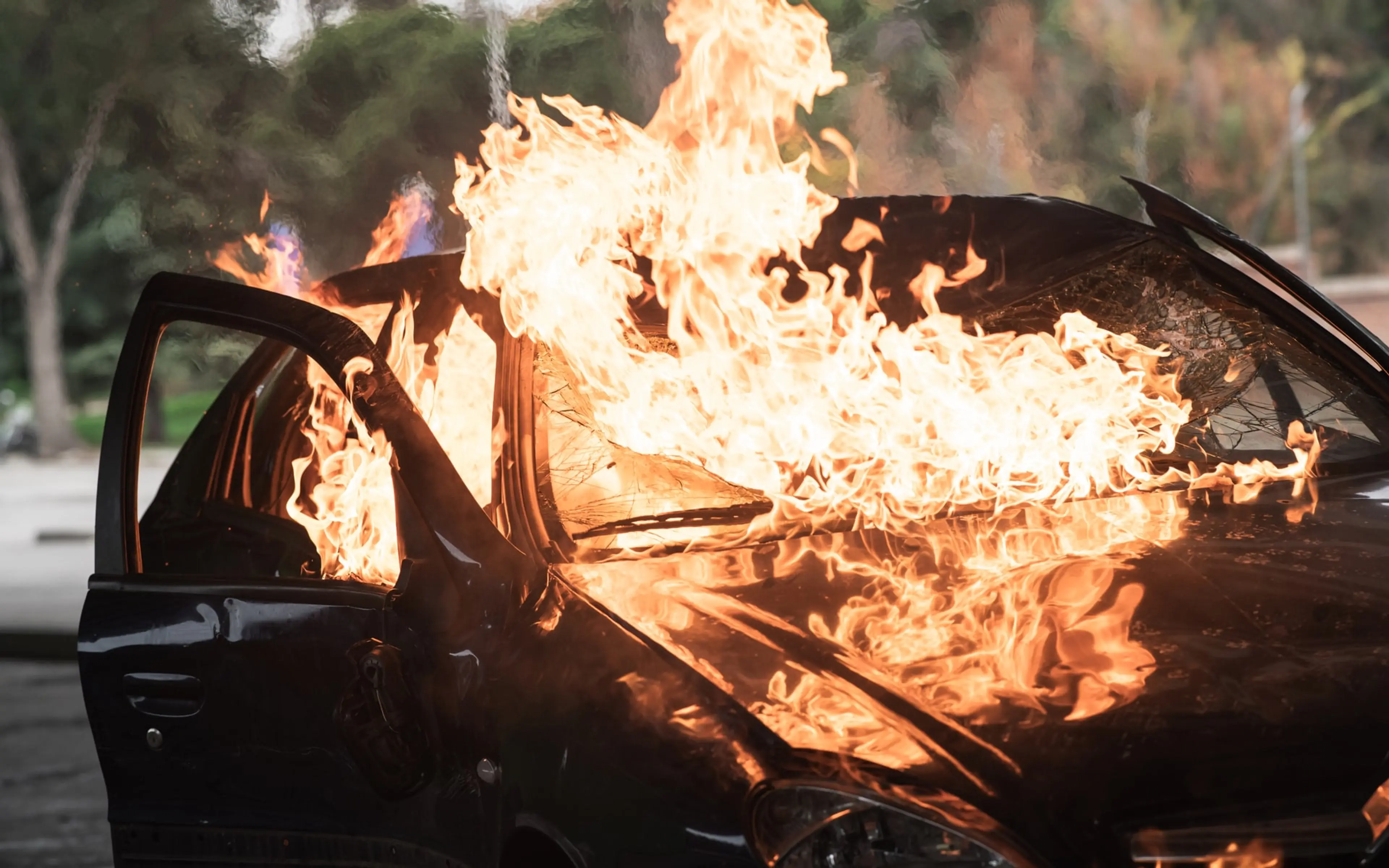 A car burns beside a road in an official still from the 2026 Spanish thriller Collision Course.