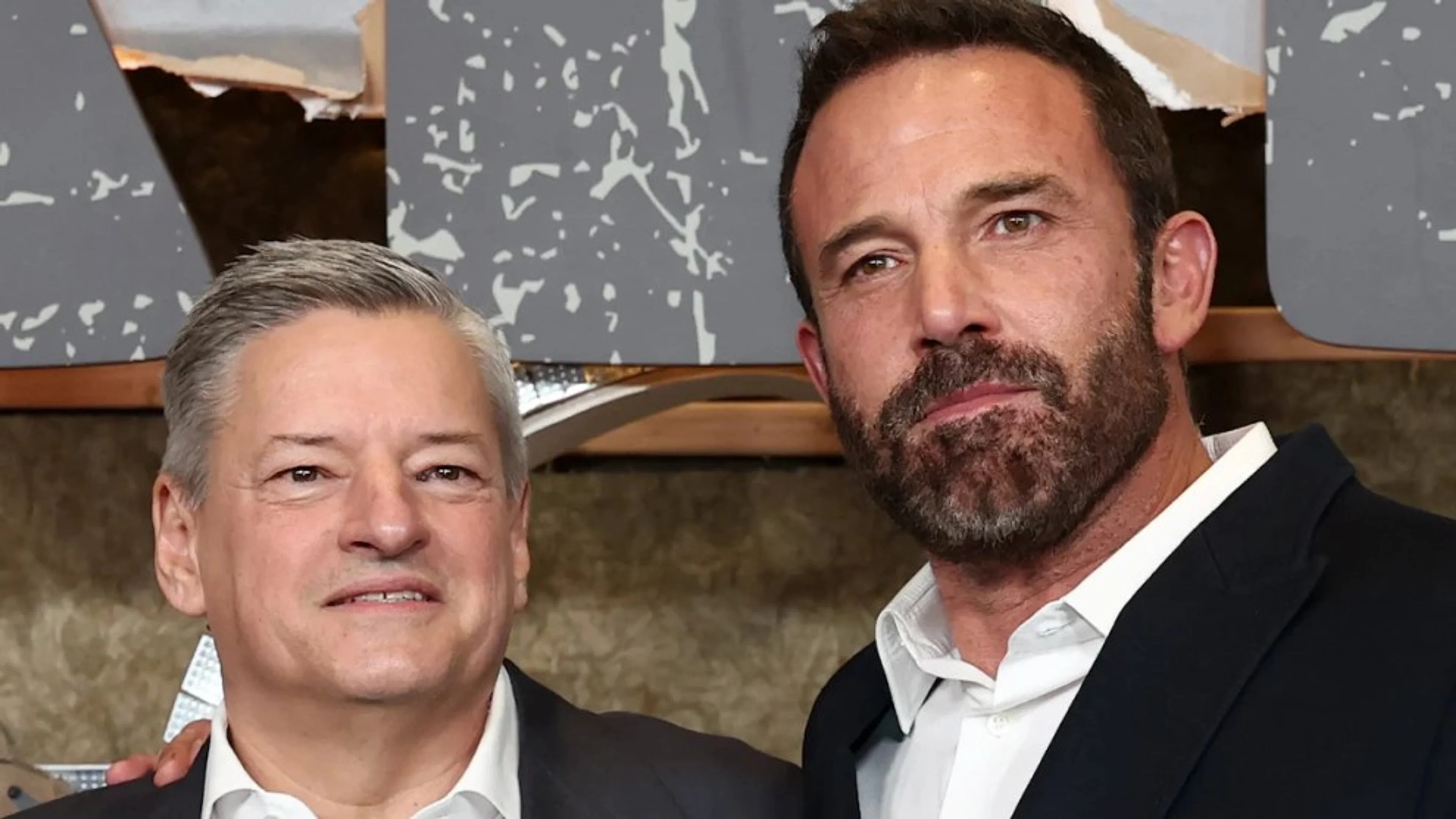 Netflix co-CEO Ted Sarandos stands beside Ben Affleck at a Netflix premiere.