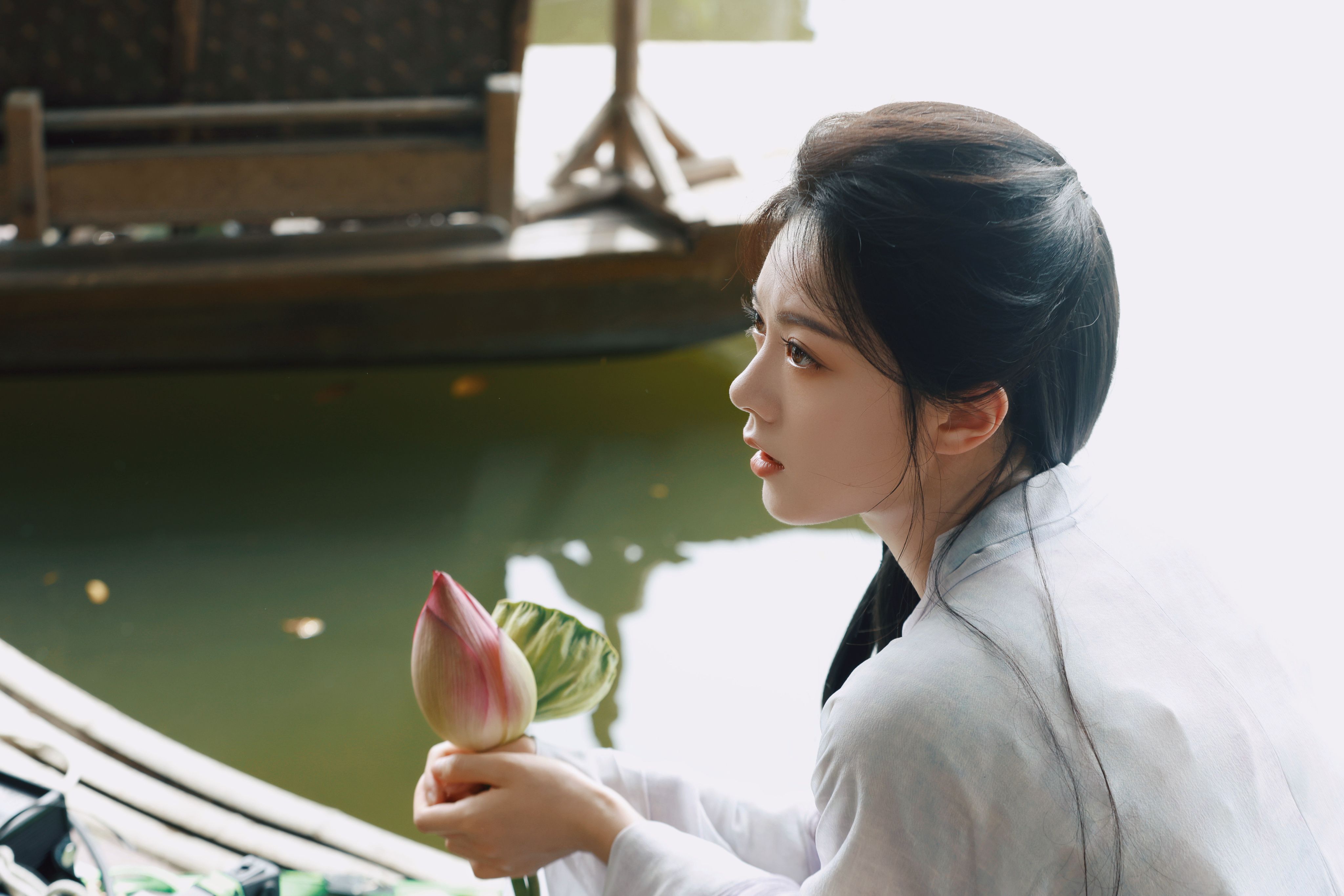 Zhao Jinmai holds a lotus bud in a separate A Journey to Glow promotional portrait.