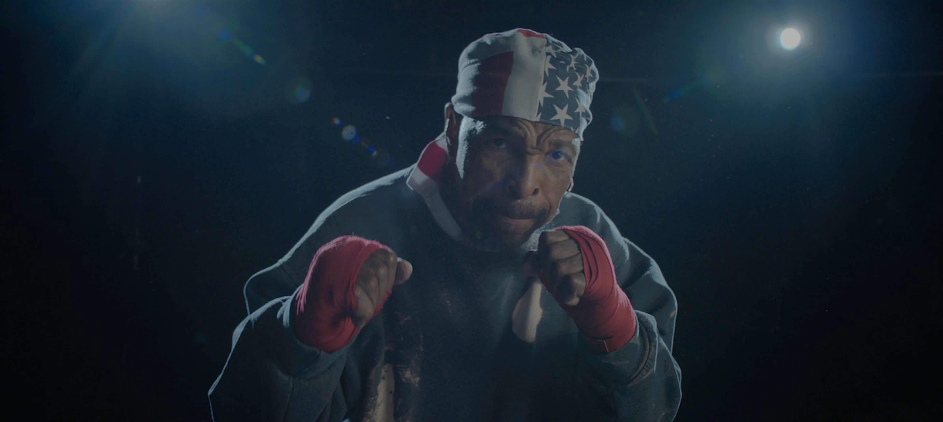 Mr. T raises his fists while wearing an American-flag bandana and red boxing wraps.