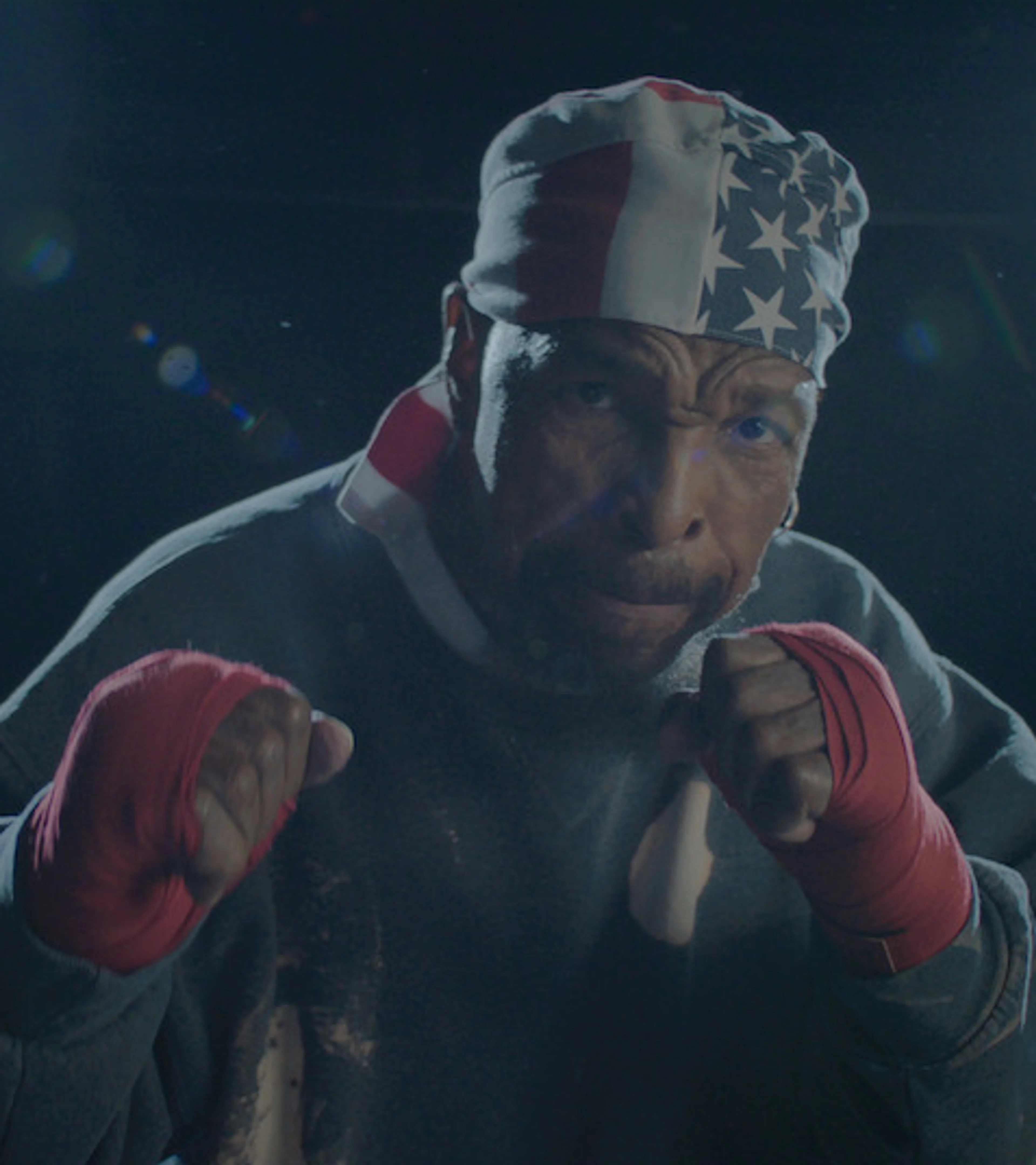 Mr. T raises his fists while wearing an American-flag bandana and red boxing wraps.