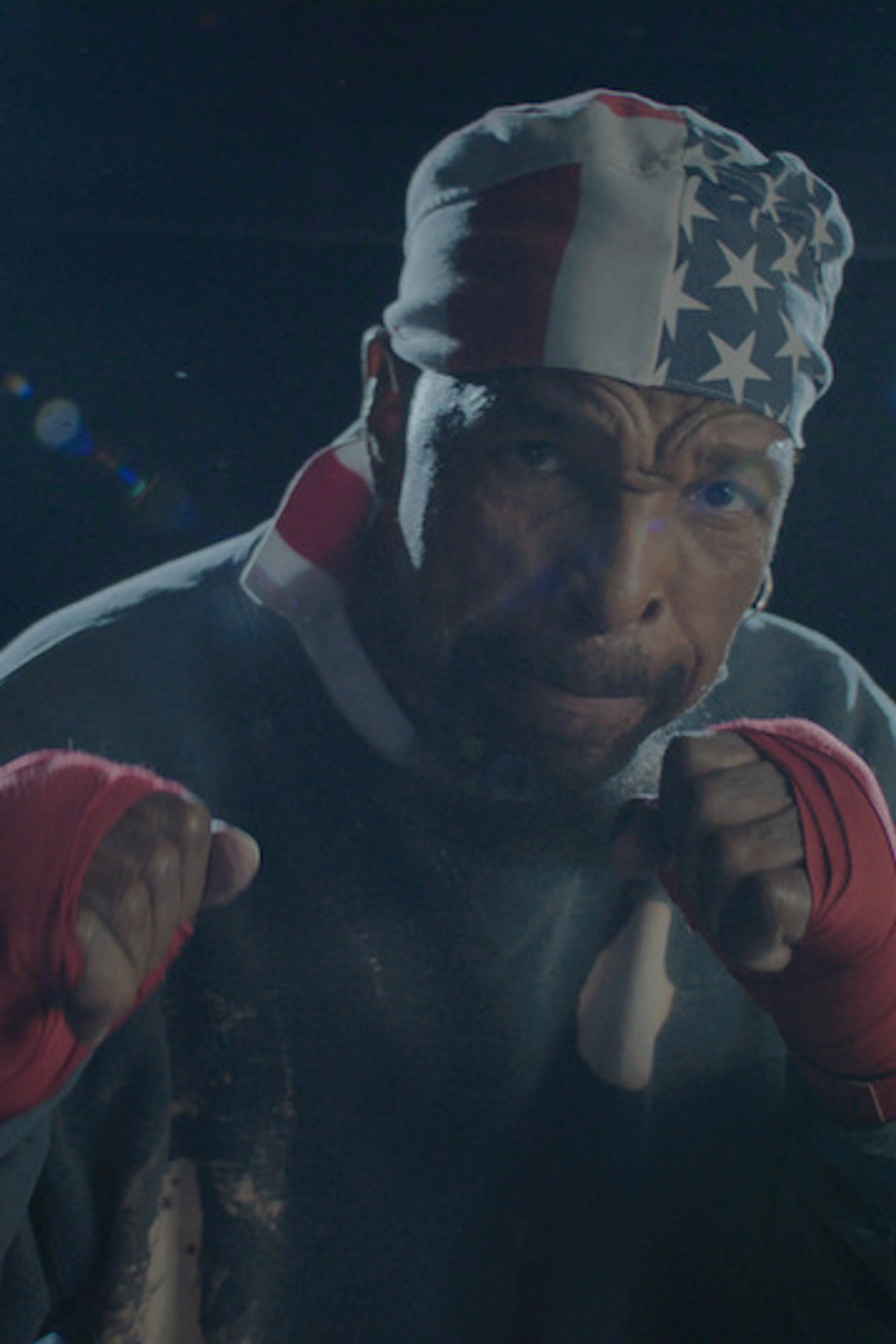 Mr. T raises his fists while wearing an American-flag bandana and red boxing wraps.