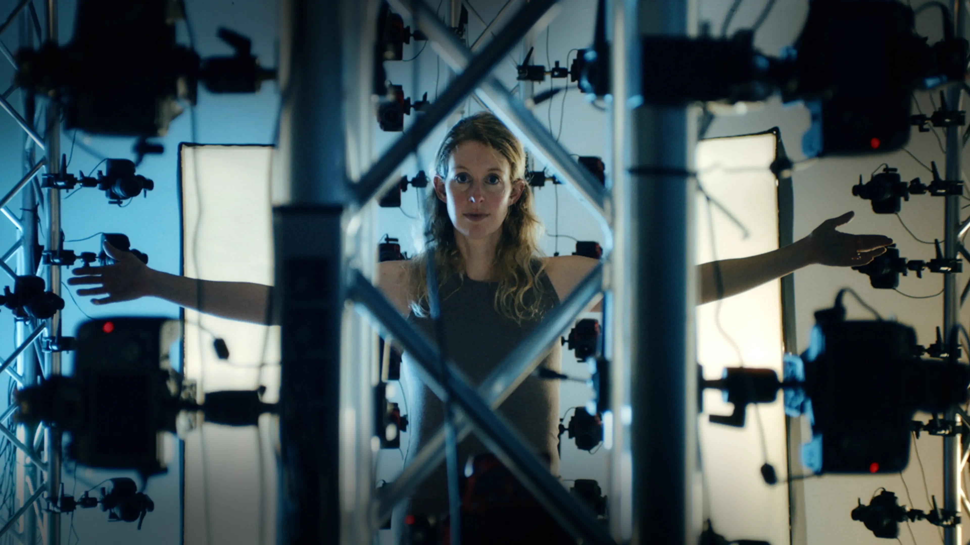 Elizabeth Holmes stands inside a ring of cameras and lights in the You Can See Everything trailer.