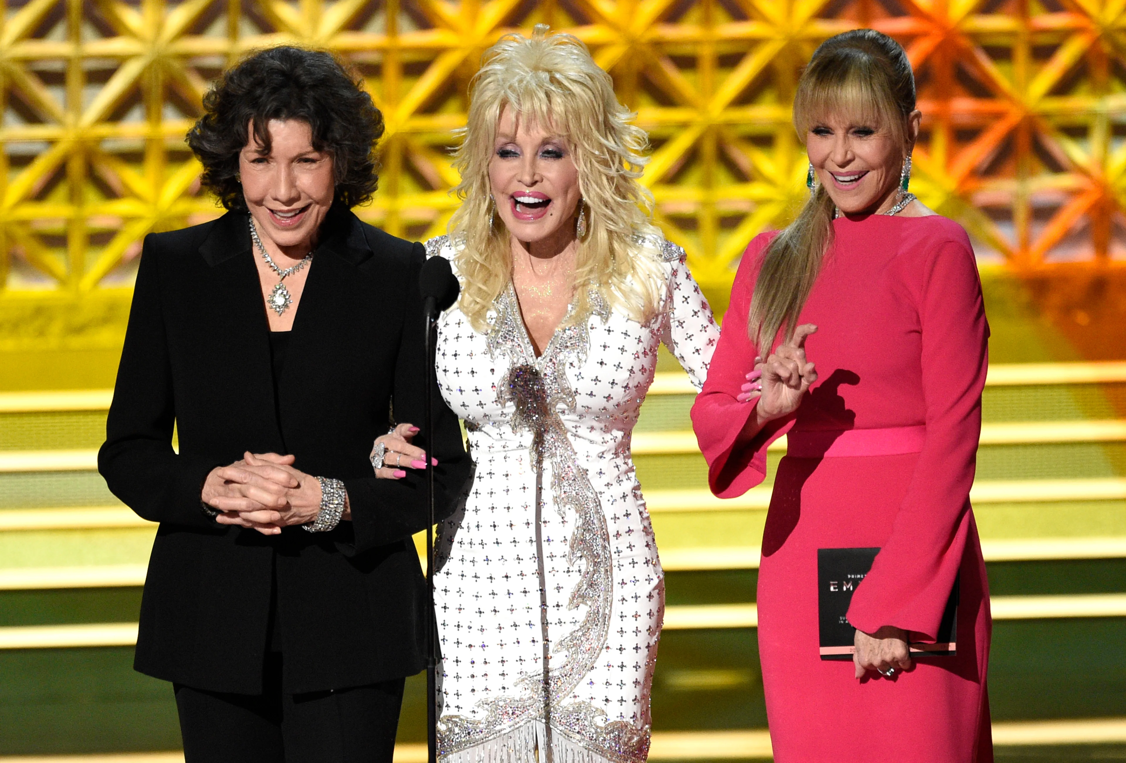 Dolly Parton stands with Lily Tomlin and Jane Fonda at the 69th Primetime Emmy Awards in 2017.
