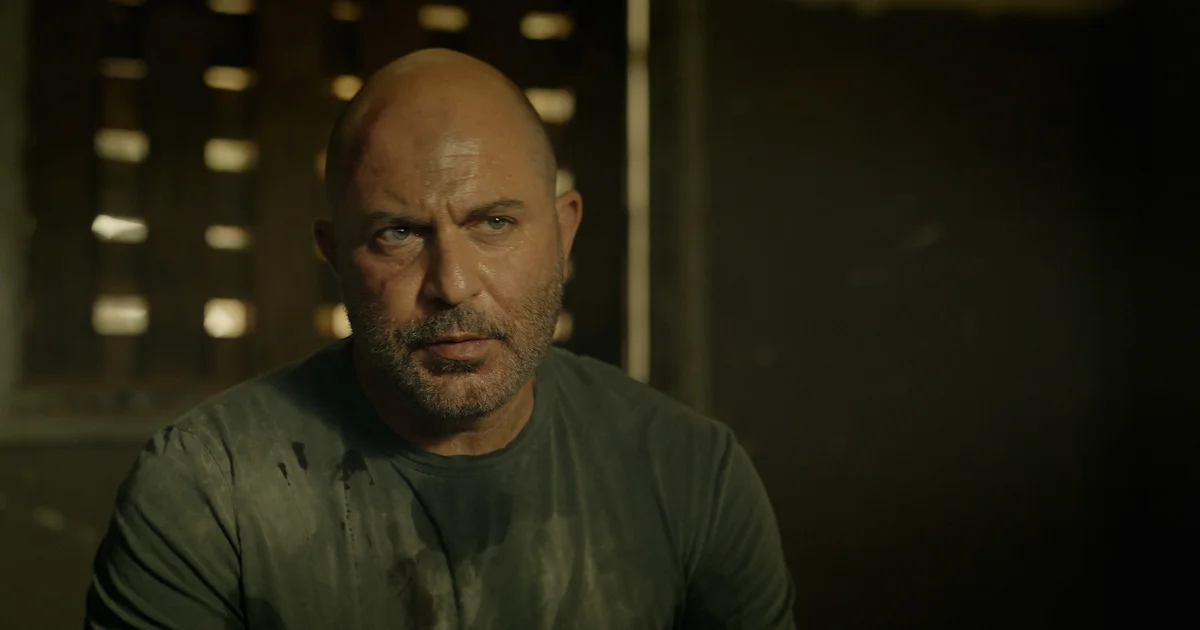 Doron sits inside a dim room and looks ahead in Fauda Season 5.