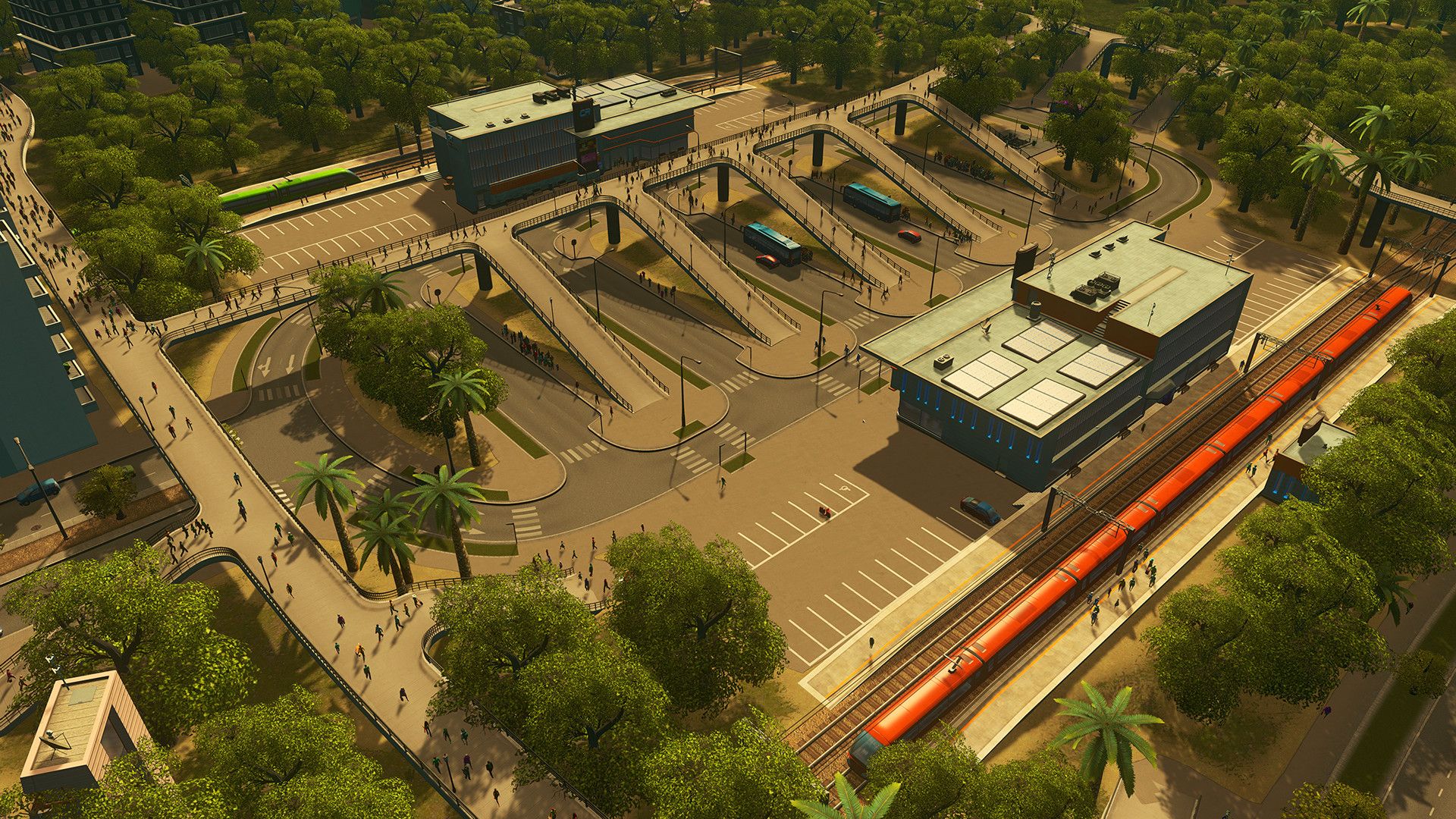 A train passes a station next to roads and buildings.